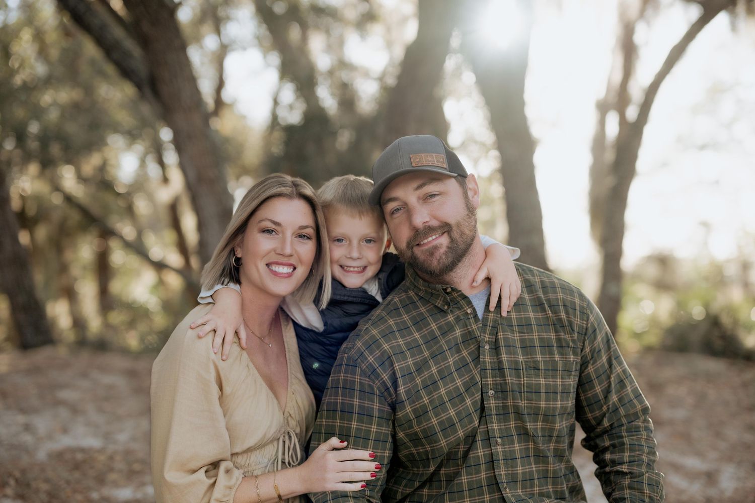 A family shares a joyful moment together in a sunlit wooded setting.
