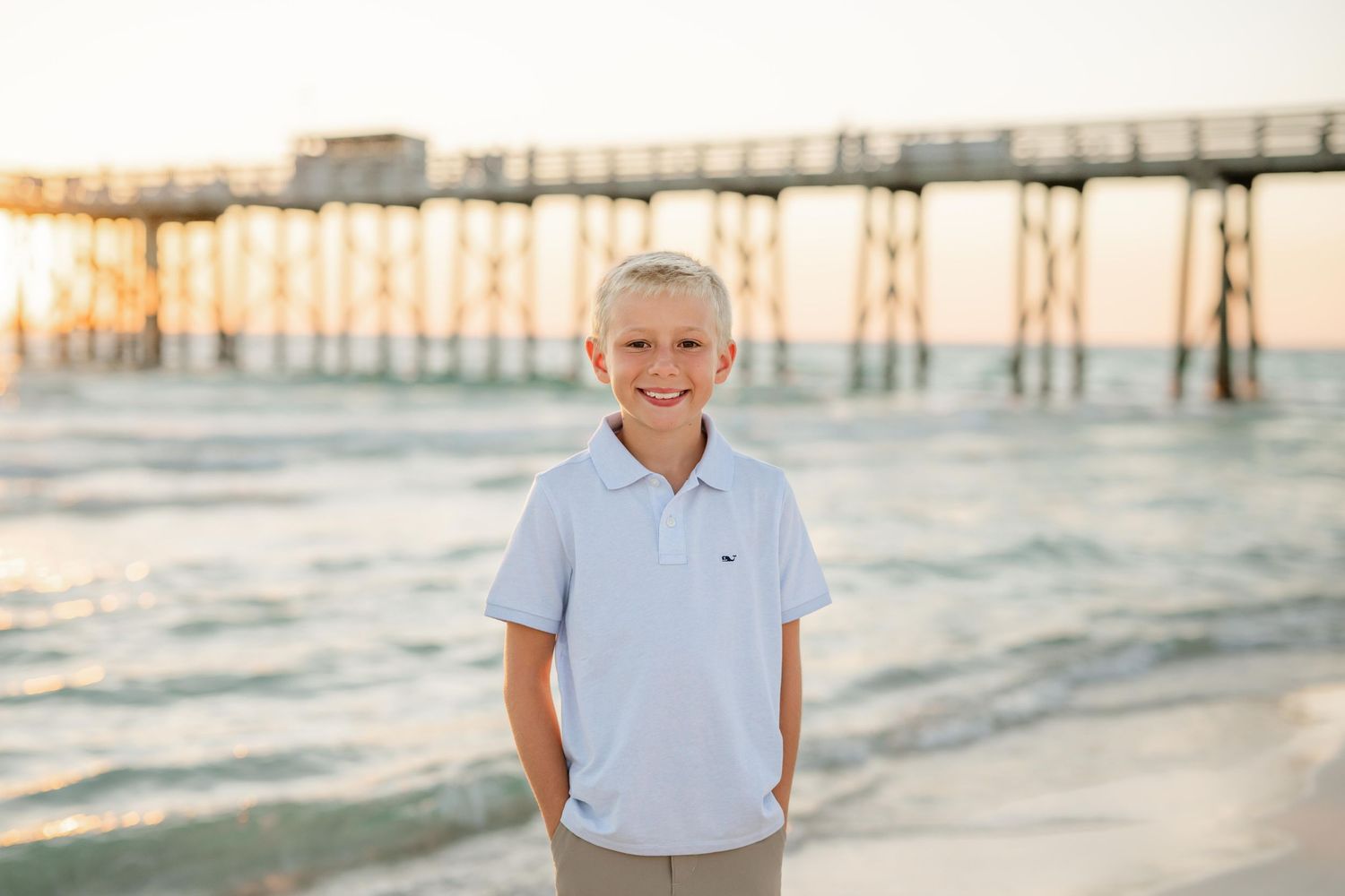 A casual beach portrait with pier and waves visible in the warm evening light.
