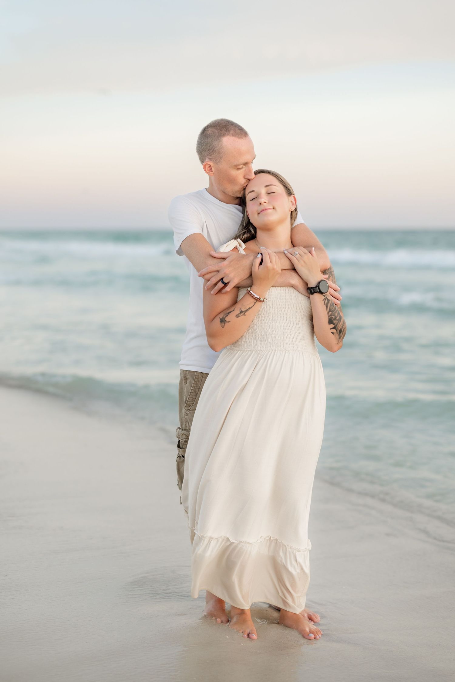 Joyful moment between couple during romantic beach portrait session at dusk.