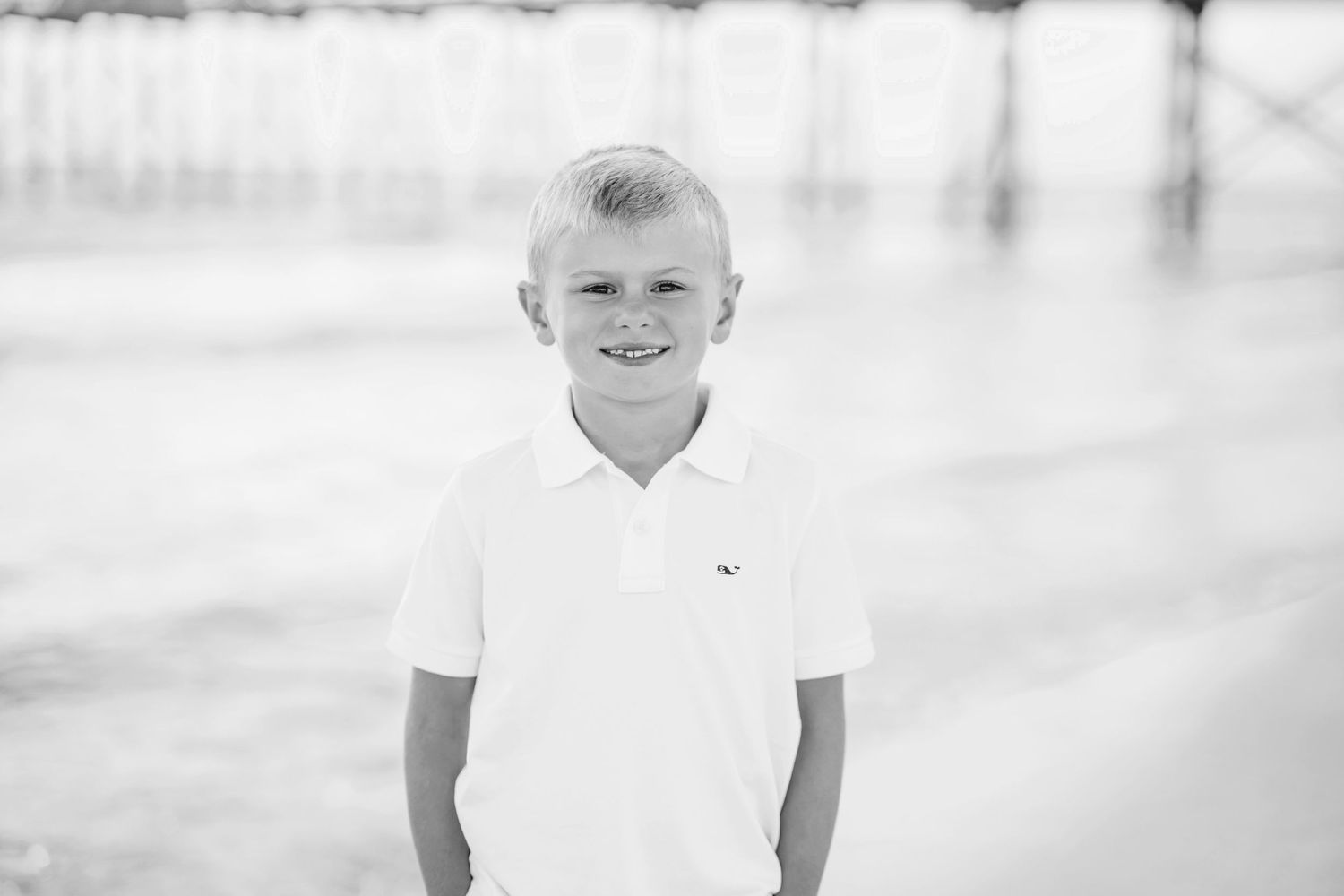 Black and white portrait of a child smiling on a sunny beach.