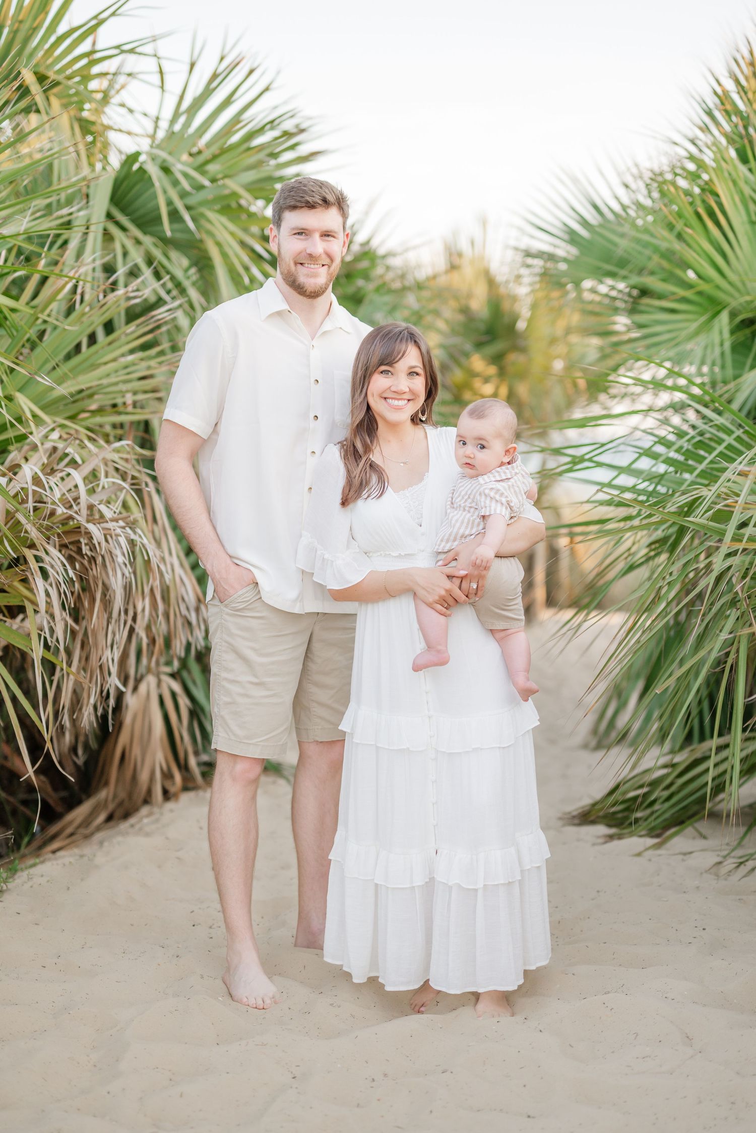 Family portrait among palm trees on a sandy beach path.