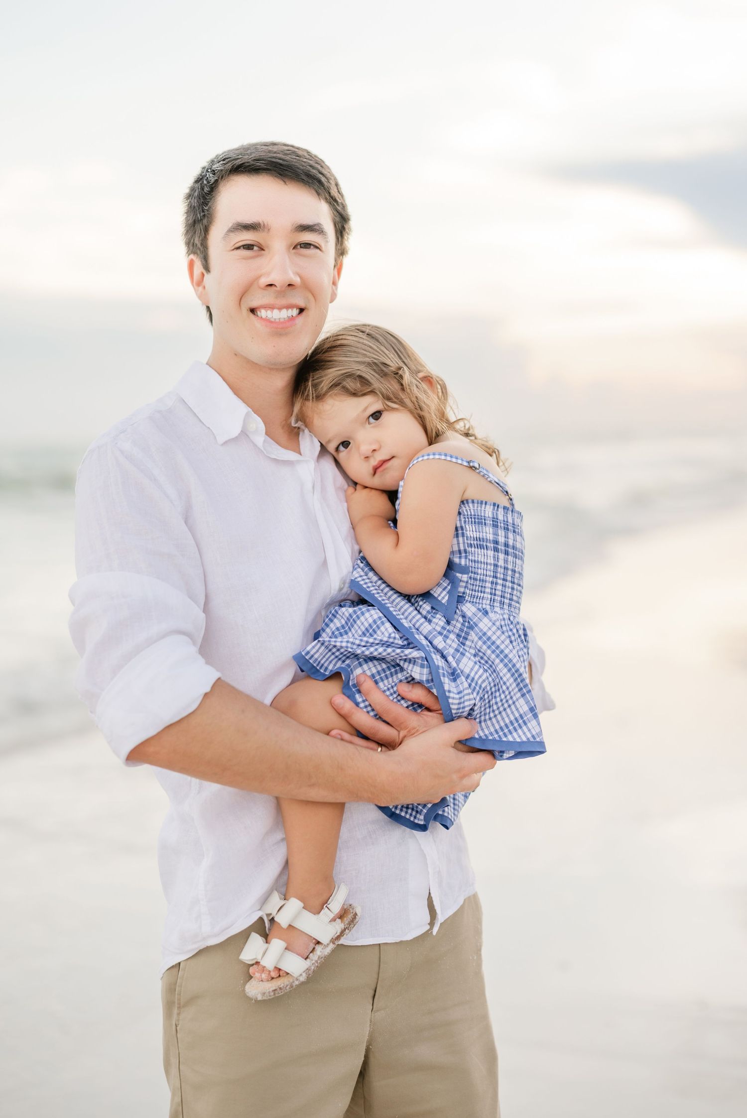 Tender family moments captured on beach with soft sunset lighting.