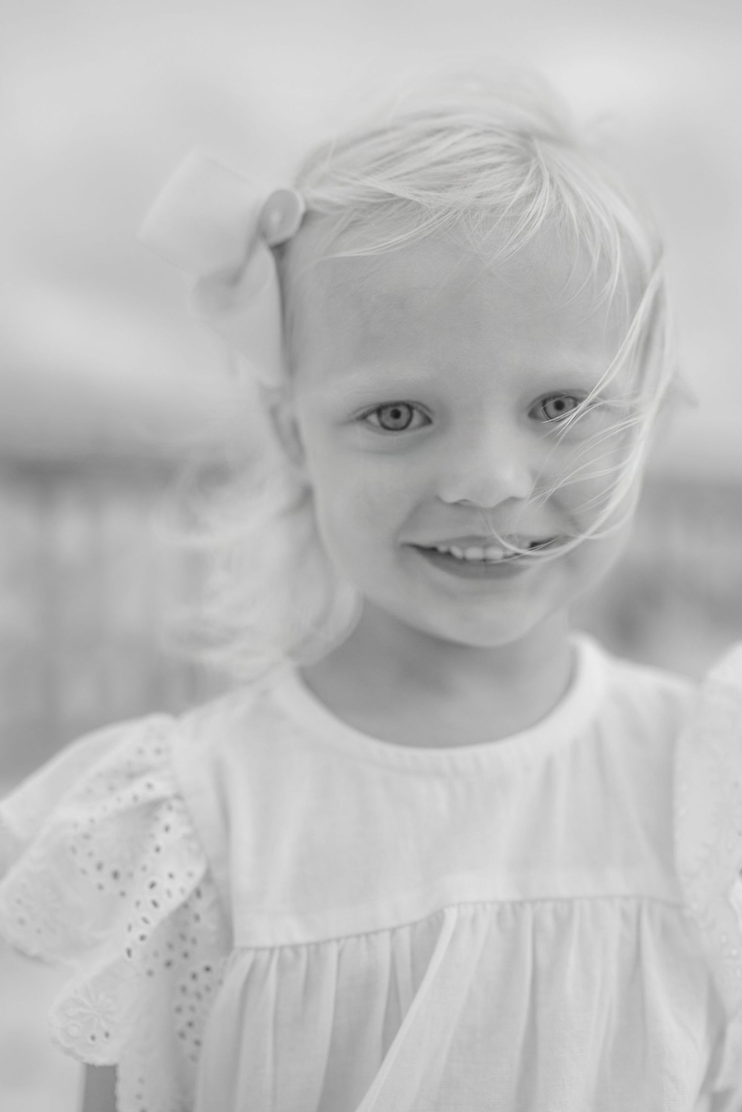 Ethereal black and white portrait of a child in white eyelet dress.