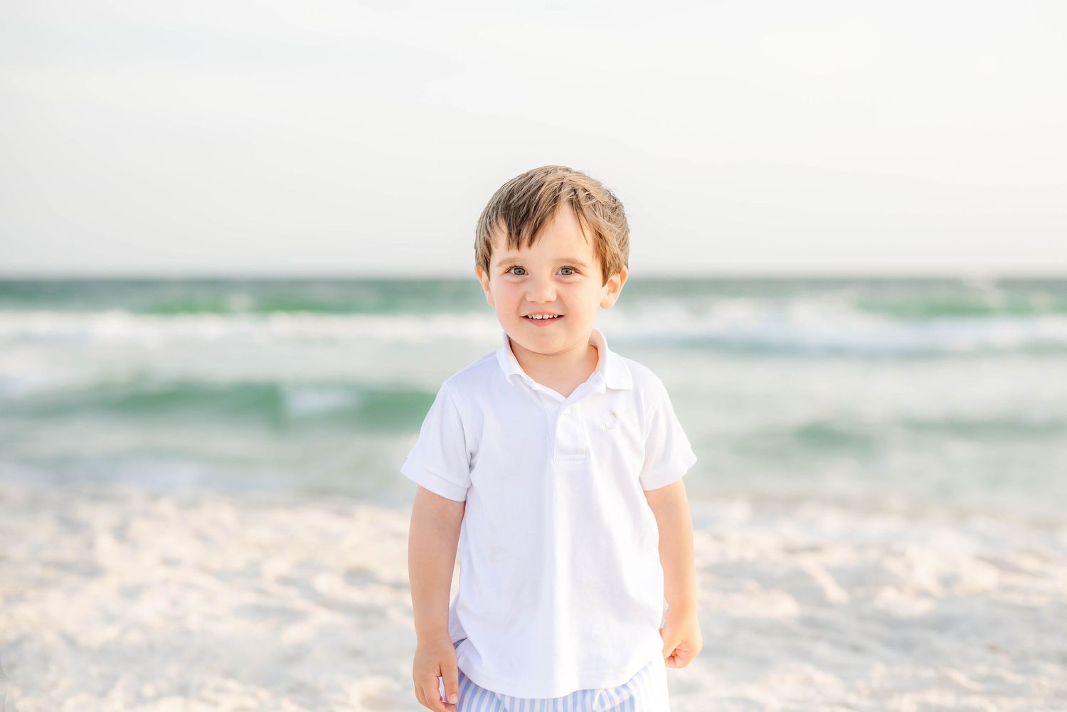 Cheerful beach portraits with ocean waves and soft natural lighting in Panama City Beach, Fl..