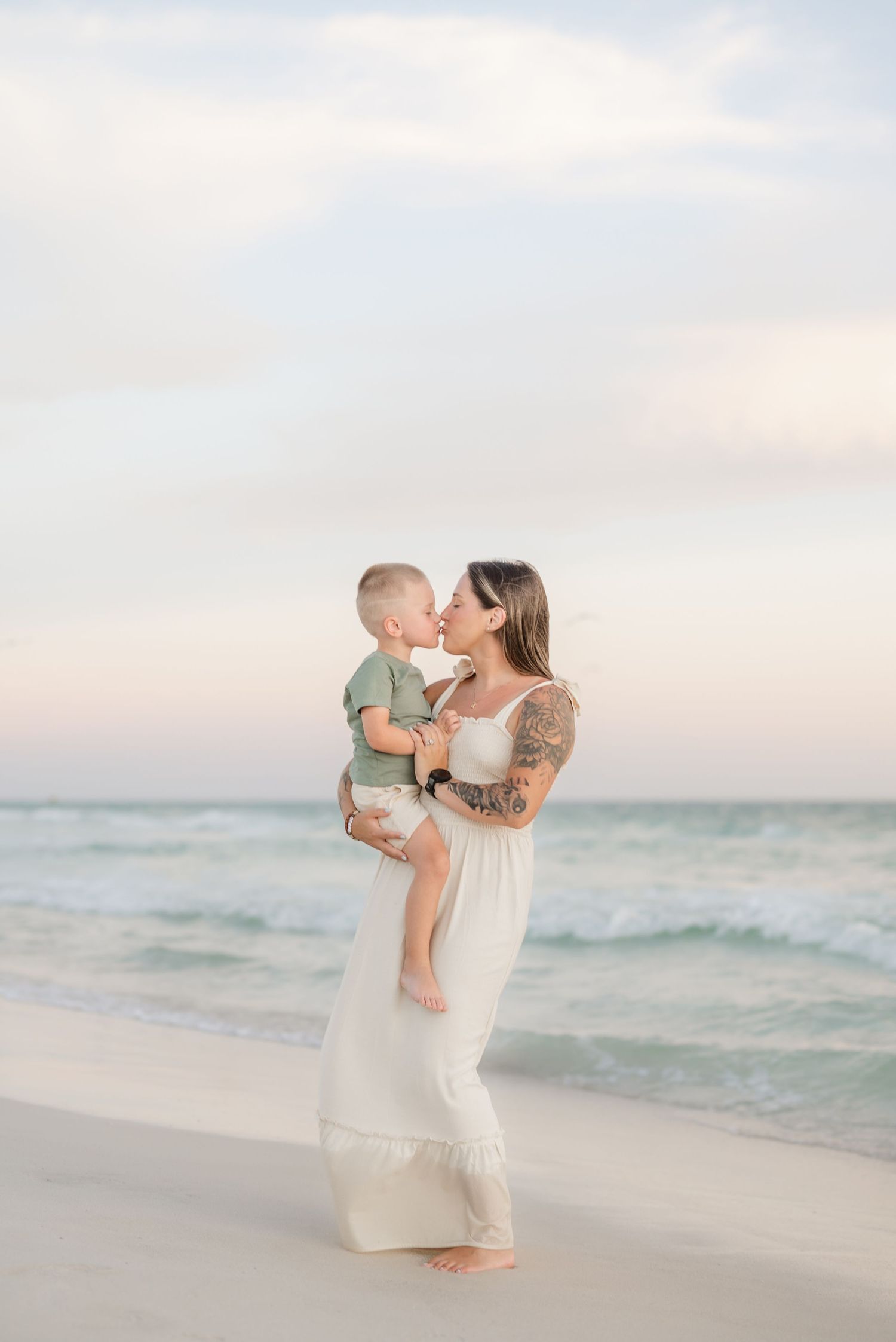 Mother and child sharing tender moment on beach at sunset.