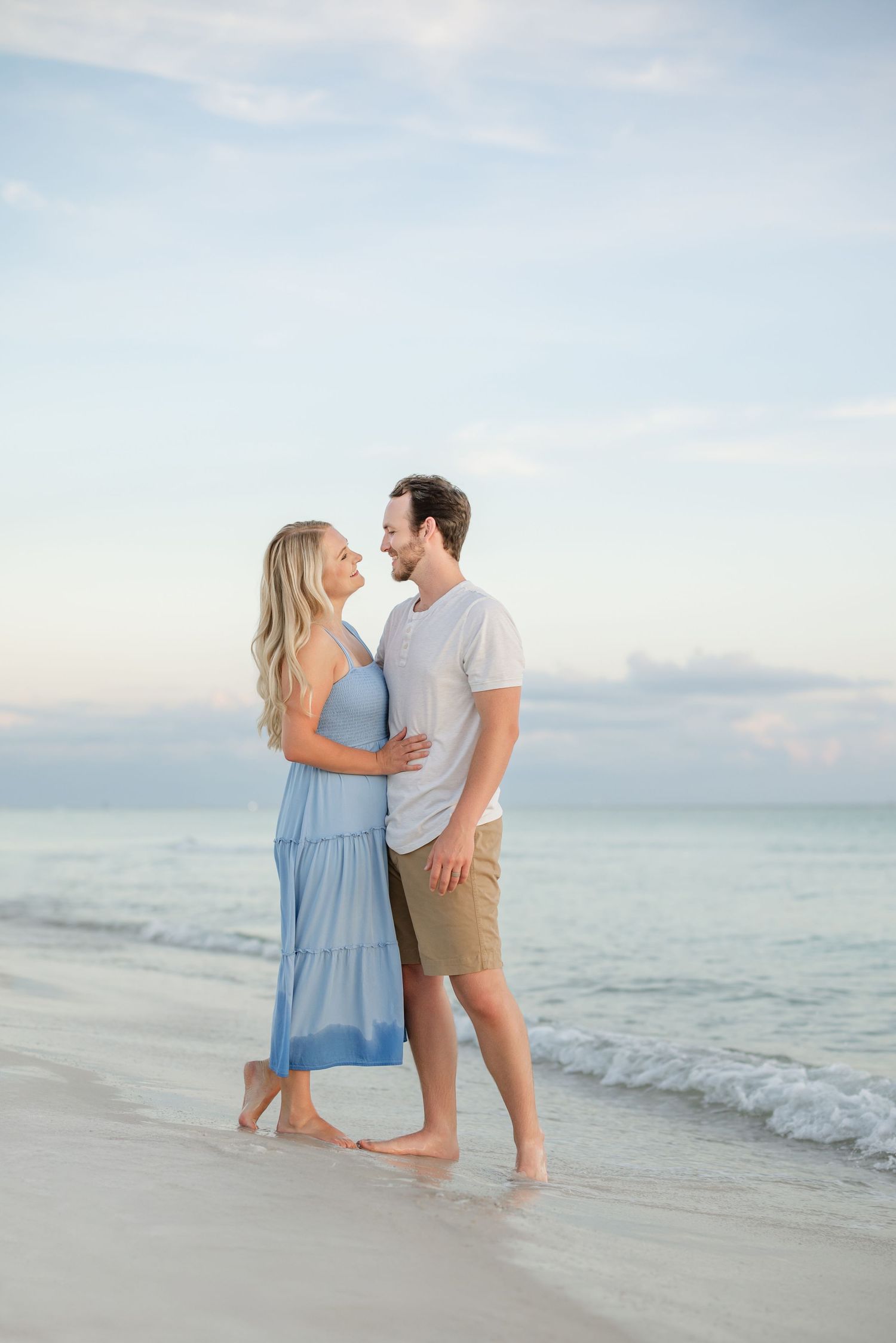 Intimate beach photography session with couple against serene ocean backdrop.