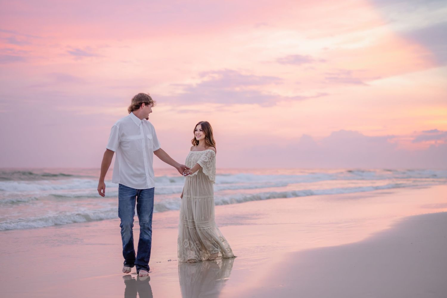 Romantic beach photoshoot at sunset with soft pink skies and gentle waves.