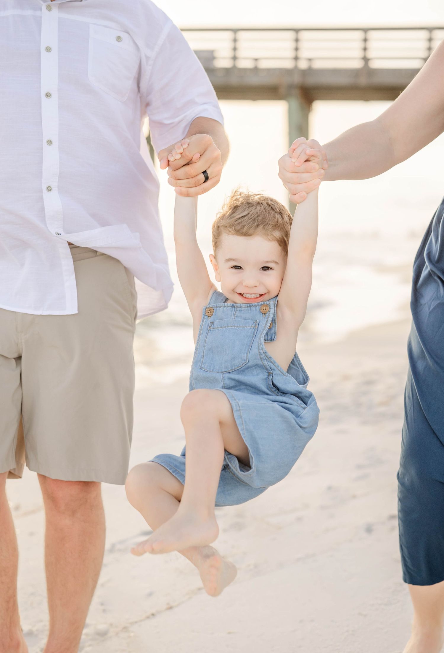 Playful family beach photos with everyone wearing coordinated white and neutral outfits.