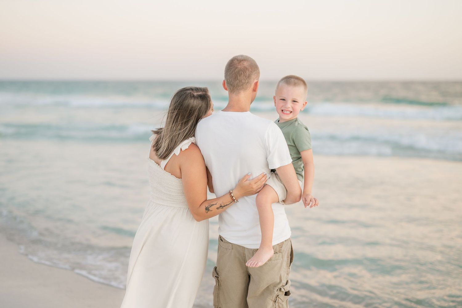 Family walking together on beach with ocean waves in background.