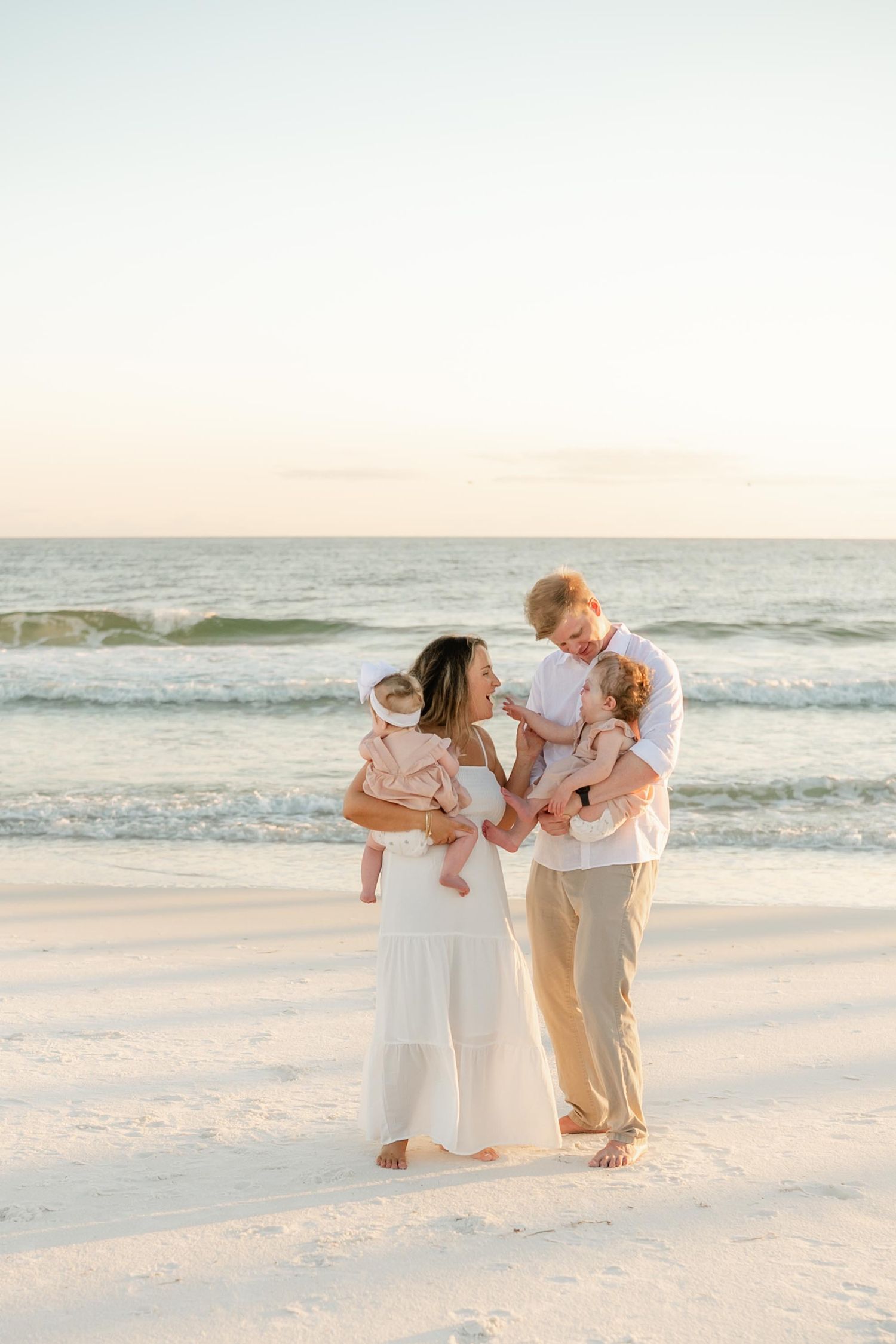 Family playing and laughing together during sunset beach photoshoot.