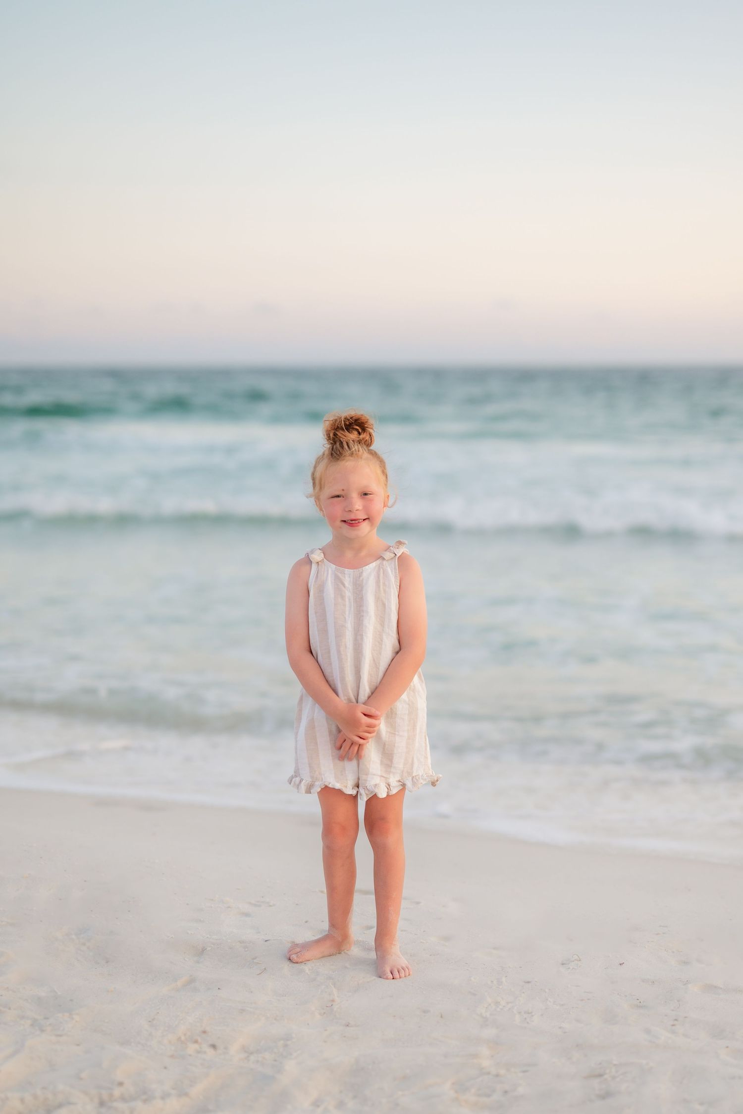 Toddler wearing white dress playing in the sand at sunset on a peaceful beach in Panama City Beach, Fl..