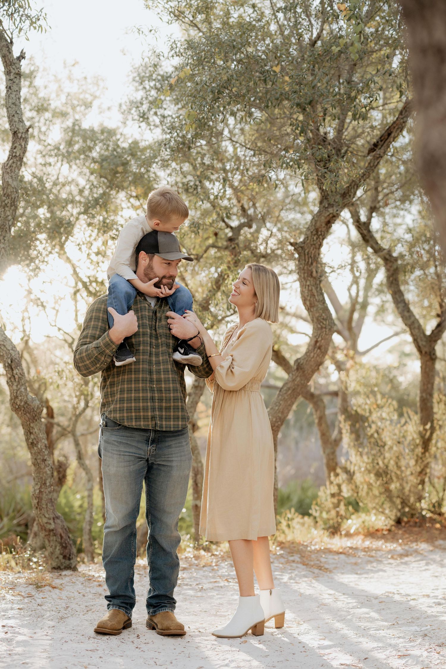 A family enjoys a playful moment together on a dirt path surrounded by trees.