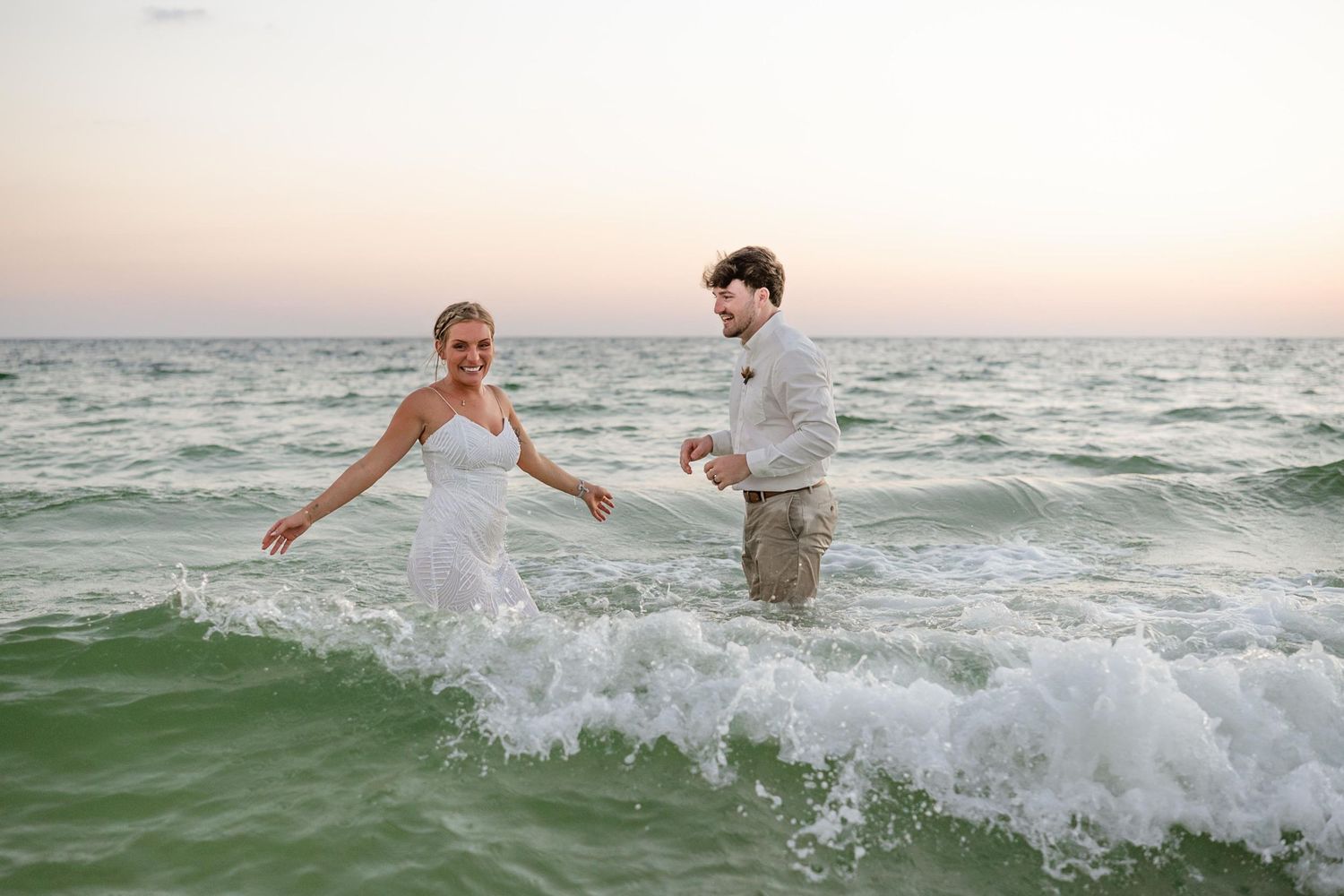 People splashing and playing in ocean waves during a beach photoshoot.