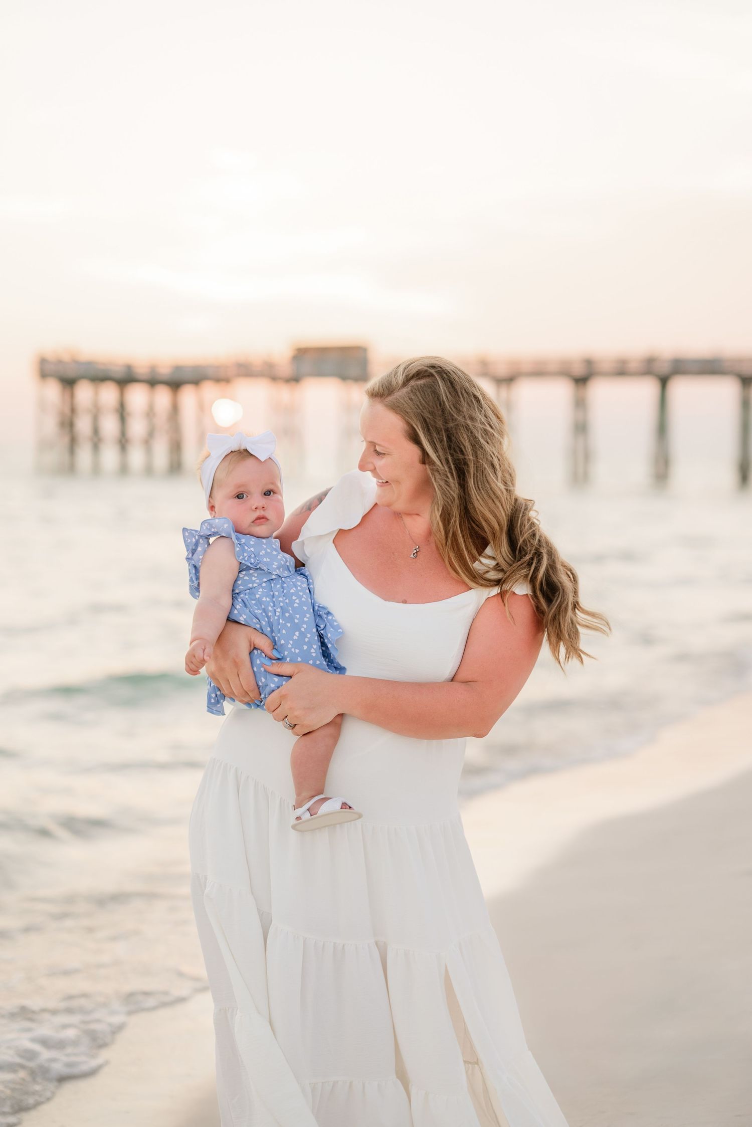 A tender moment between parent and baby on a beach at sunset.