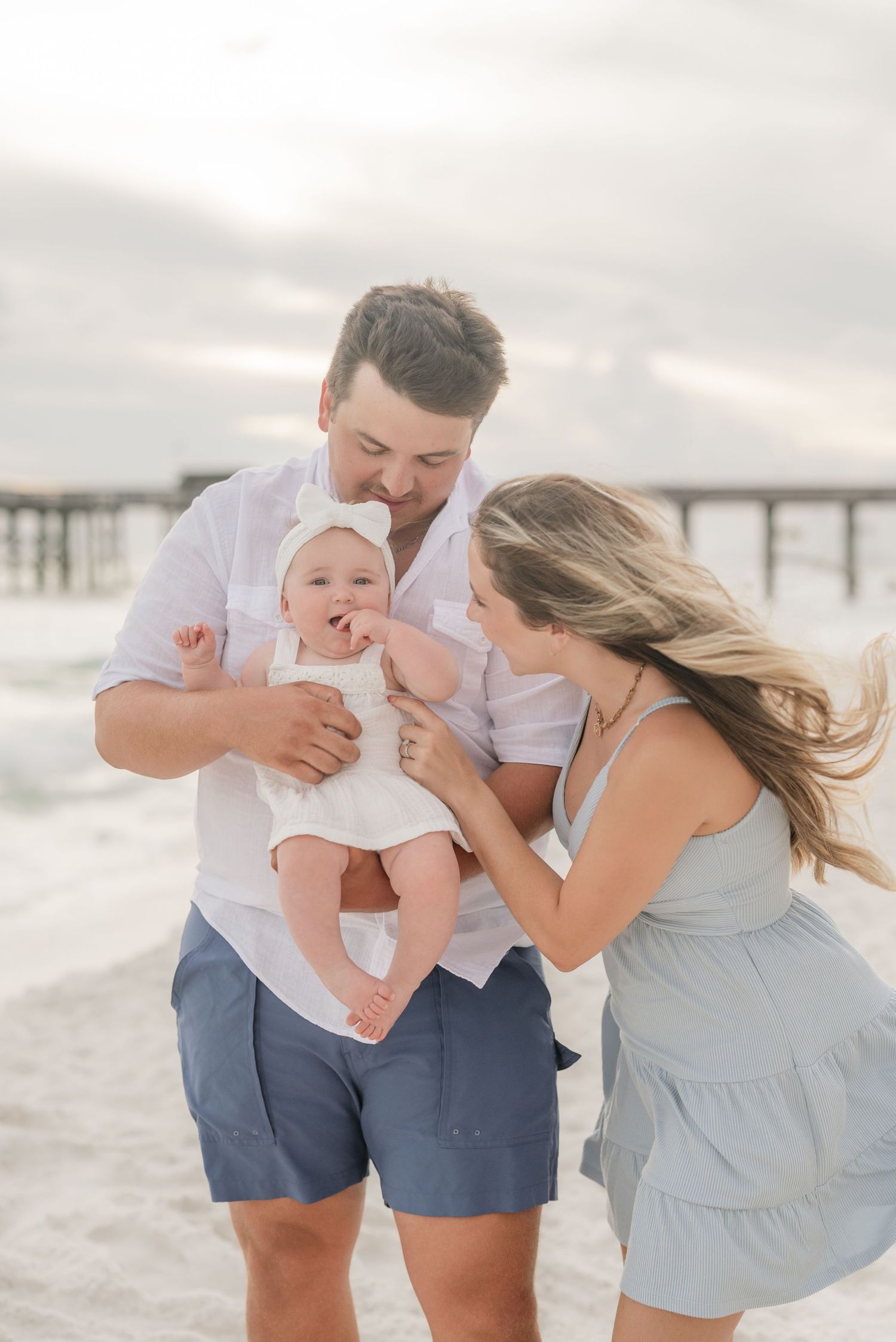 Candid family moment with laughter on beach near pier.