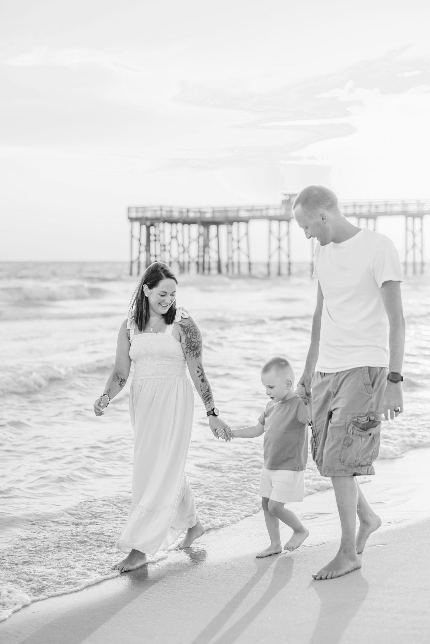 Family walking together along shoreline during sunset beach photoshoot.
