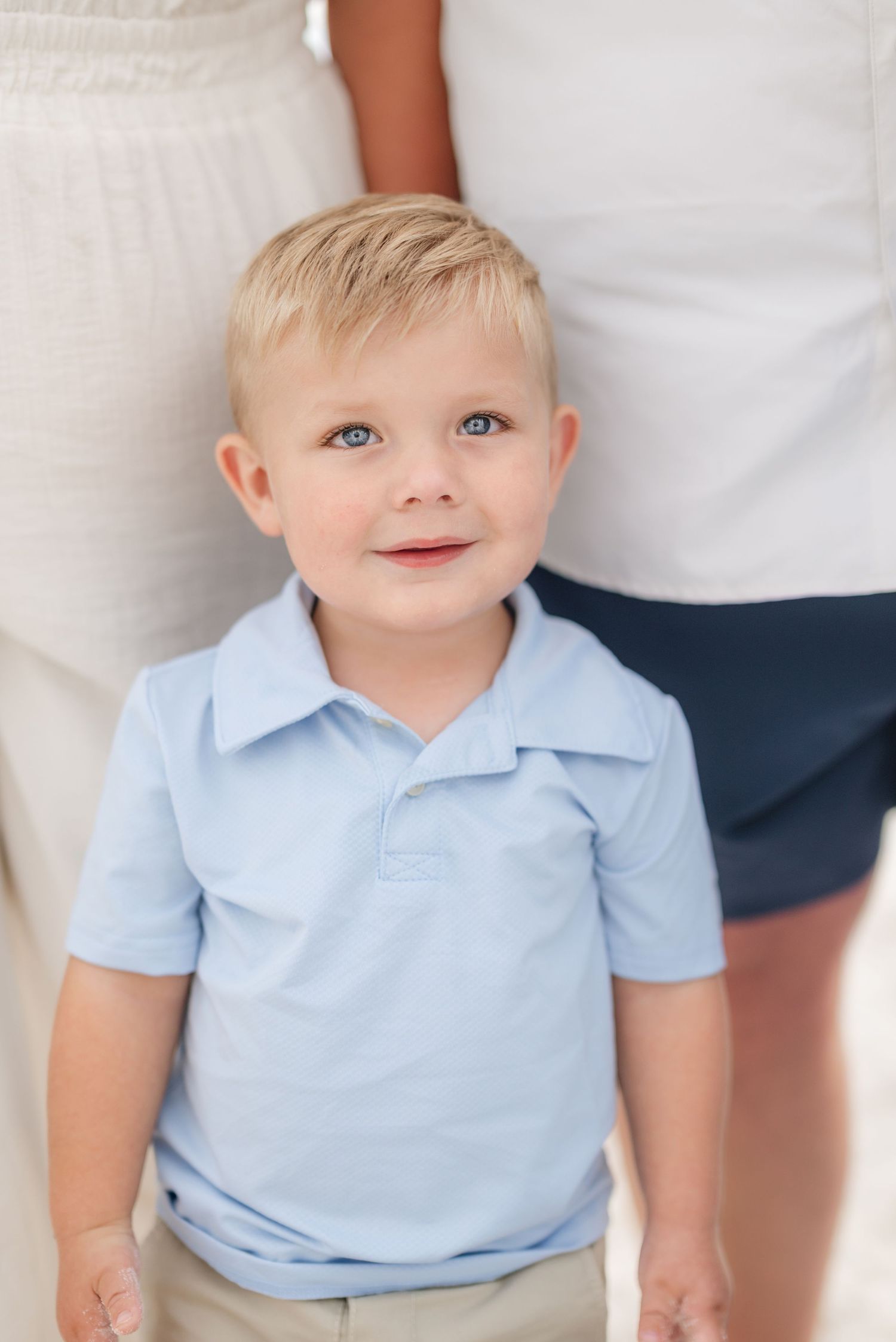 Young child in light blue polo shirt smiling at camera against white background in Panama City Beach, Fl..