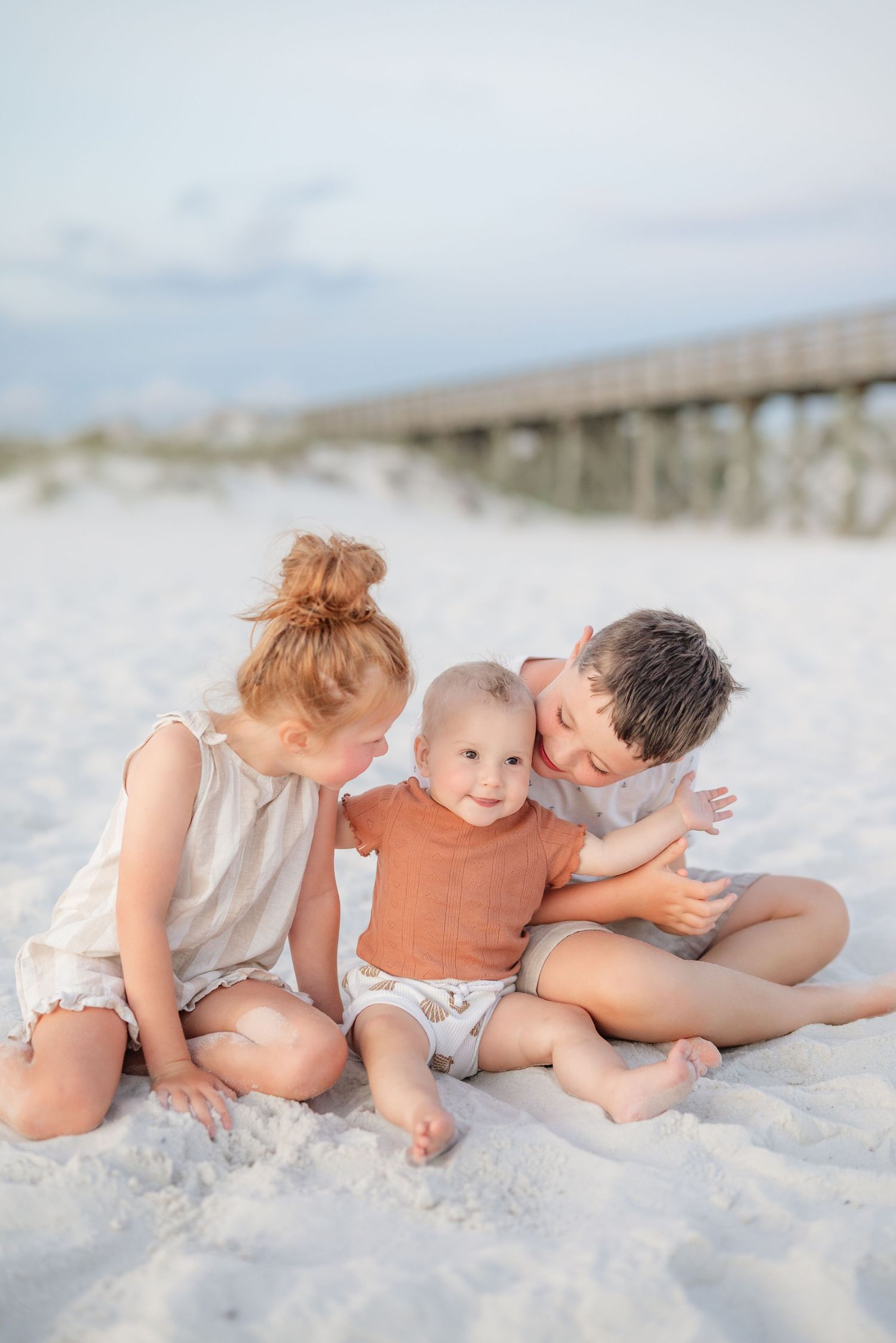 Intimate family photos laying together on pristine white sand beach.