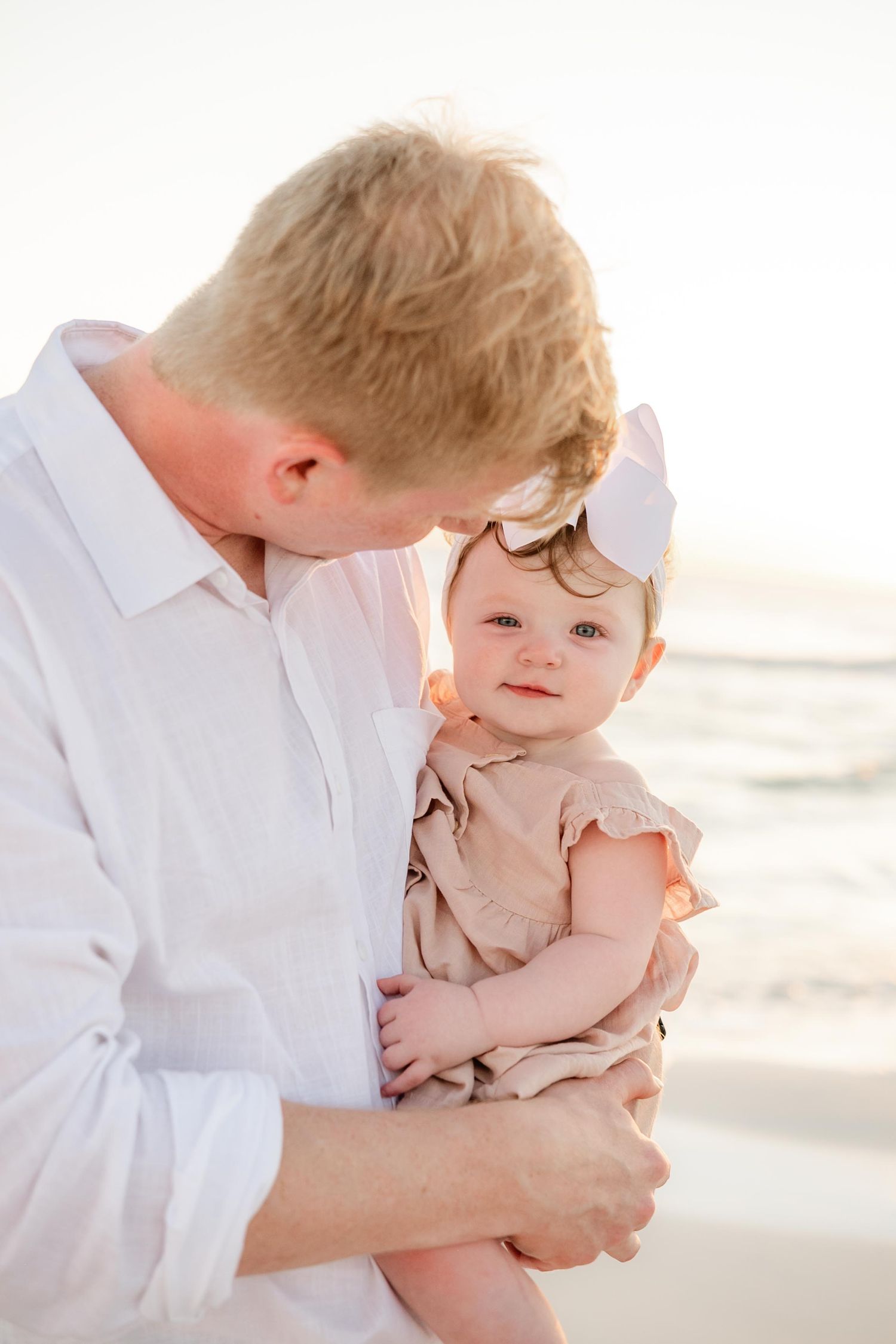 Tender parent-child moment captured during sunset beach photoshoot.