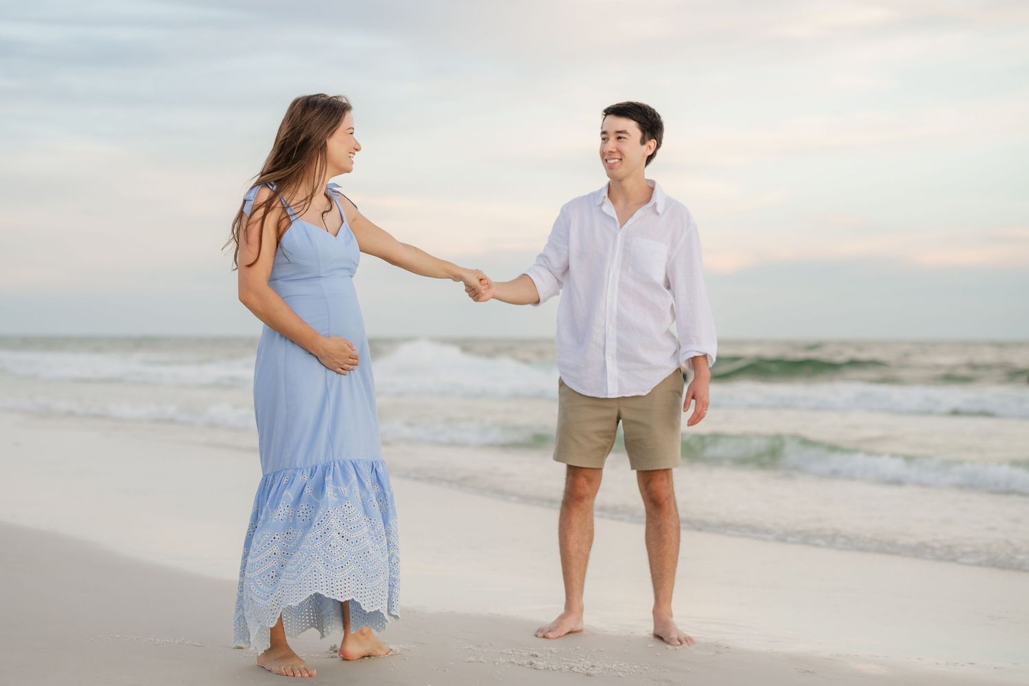 A couple enjoys a playful moment together on a sandy beach at sunset.