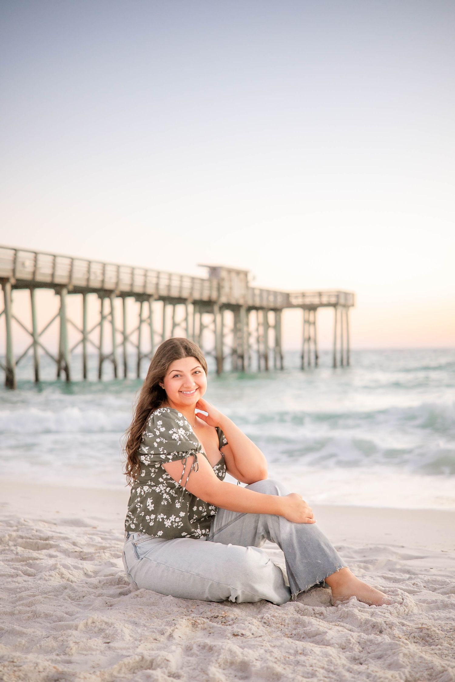 Sunset beach photography session with a weathered pier creating a beautiful coastal backdrop.