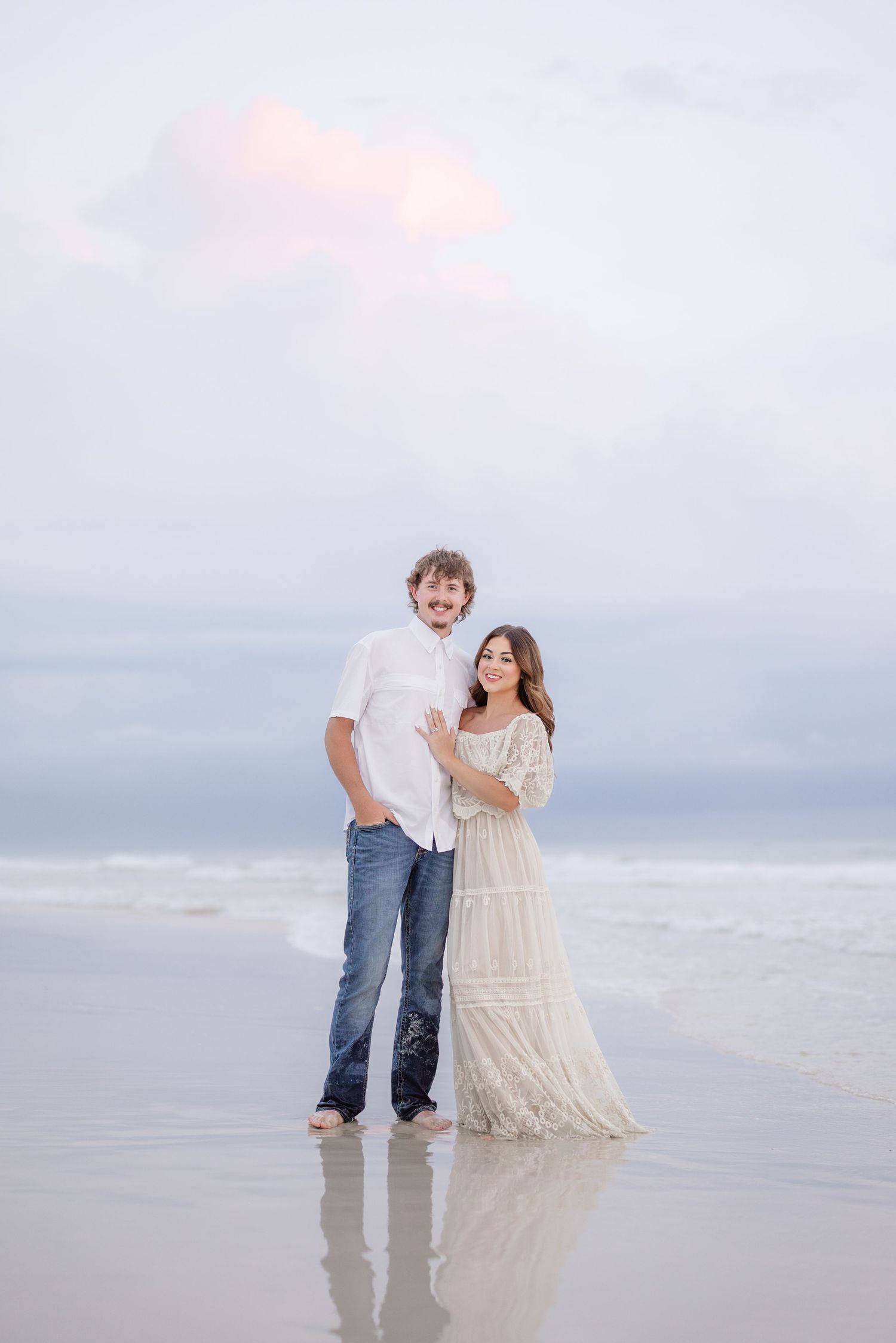 Sunset beach portrait session with couple in romantic white dress and casual attire.