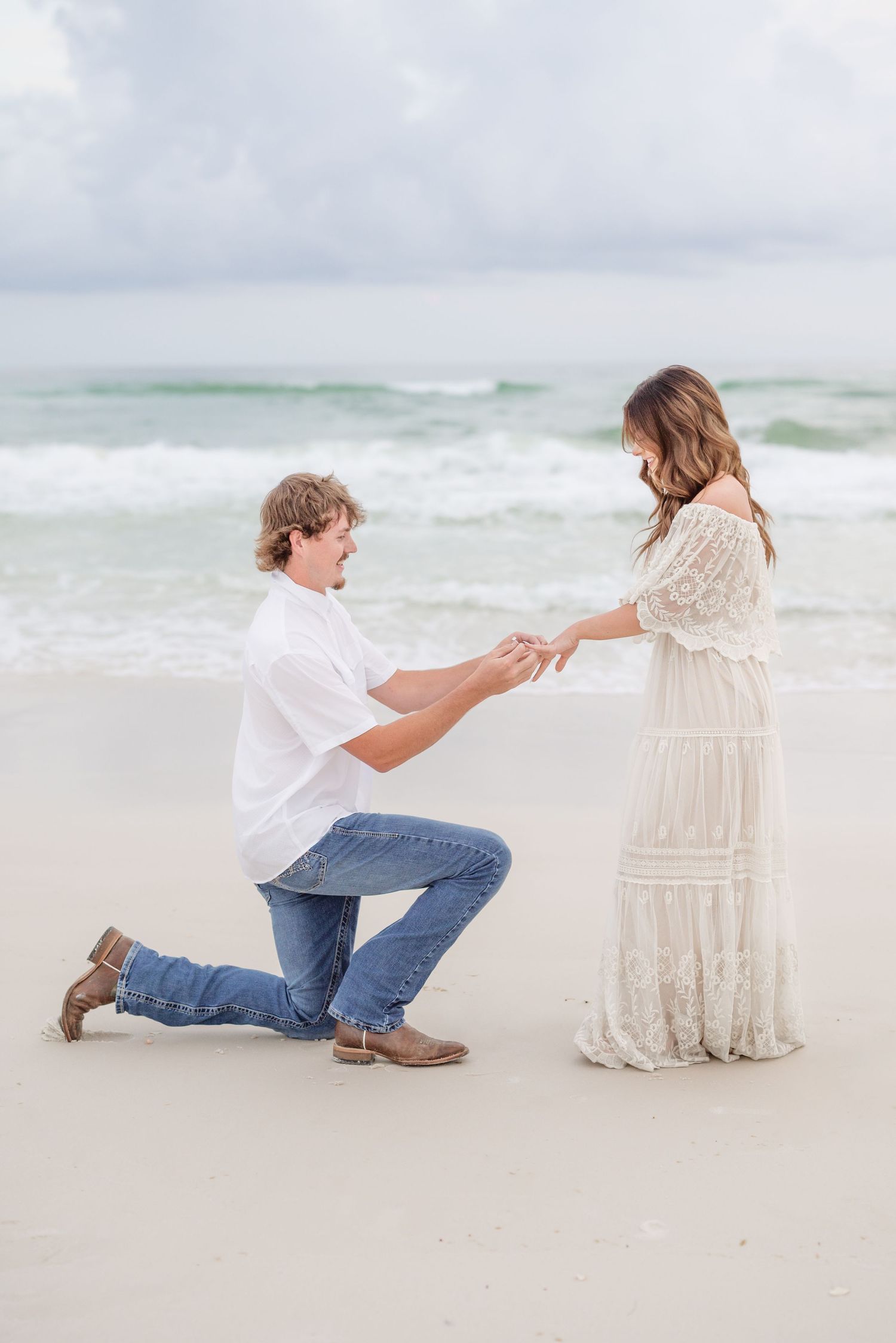 A romantic beach proposal sequence showing a person kneeling in the sand at sunset.