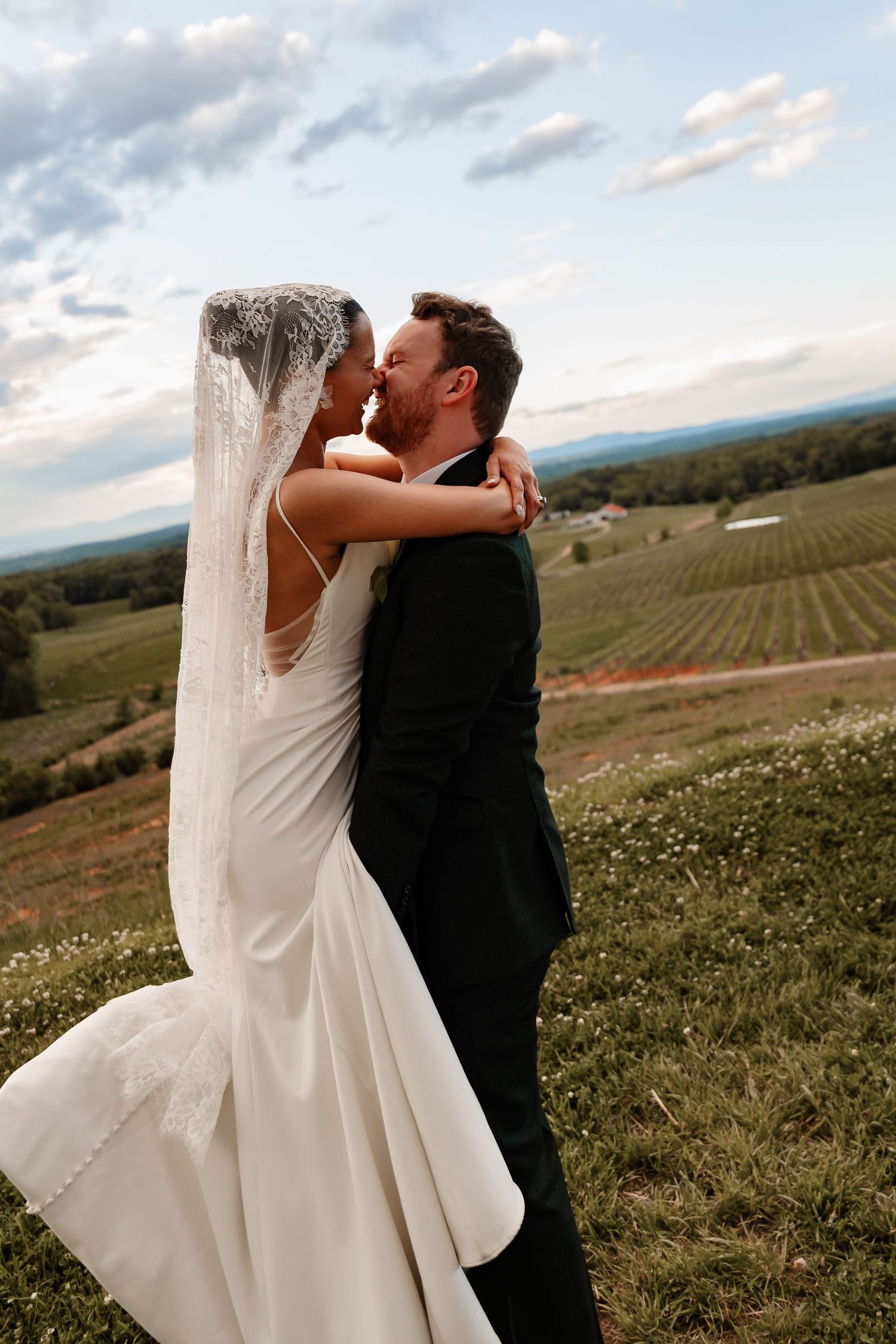 Newlyweds share intimate moment at sunset overlooking scenic vineyard landscape.
