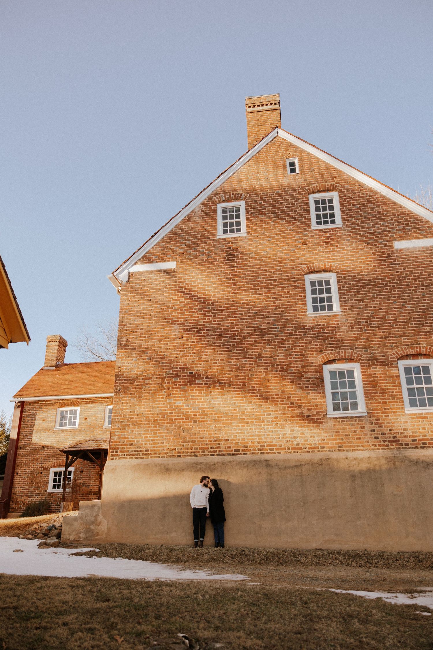 Side view of a historic brick building with white windows against blue sky.