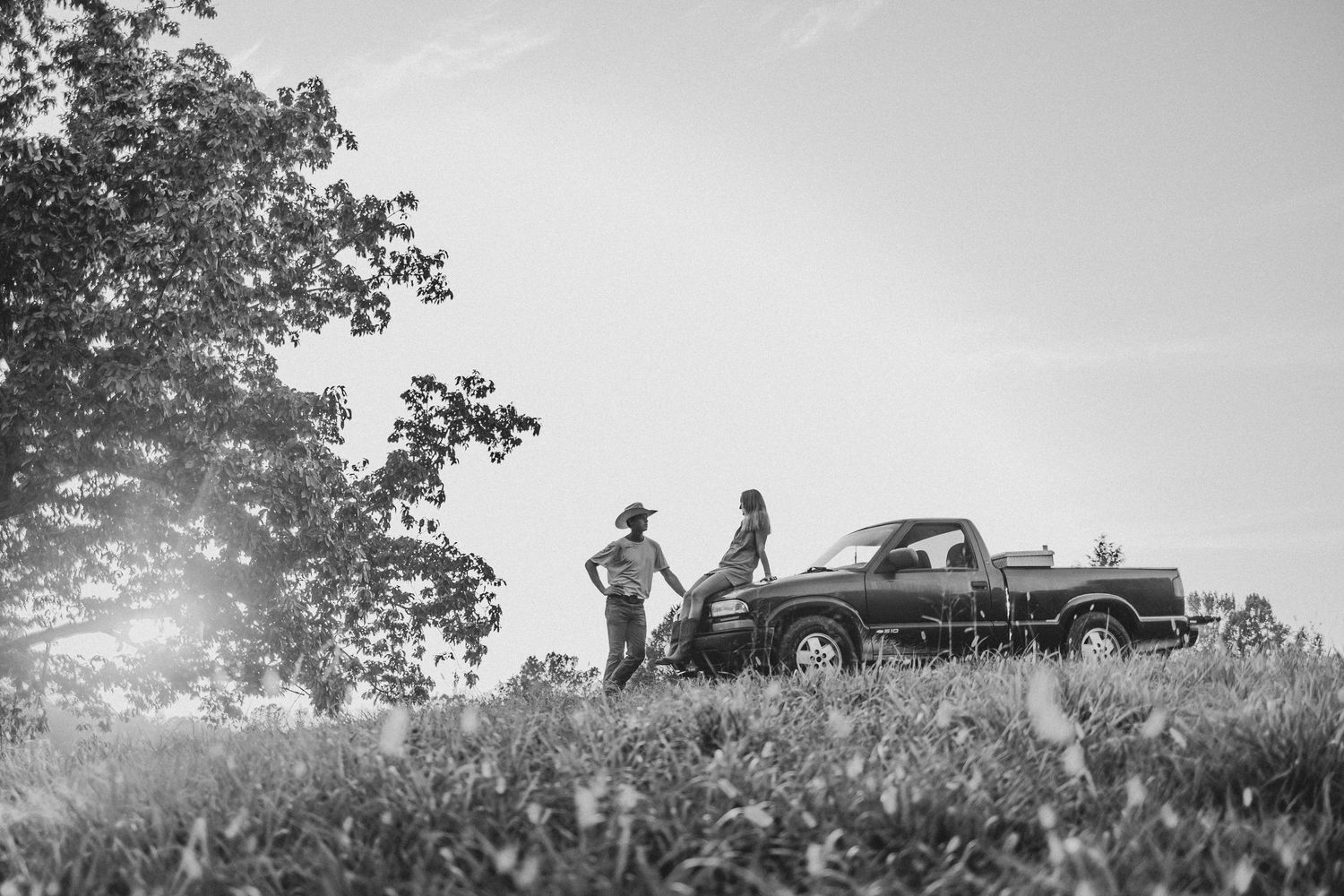 Vintage black and white panoramic sequence showing silhouettes of people and a car on a hilltop at sunset.