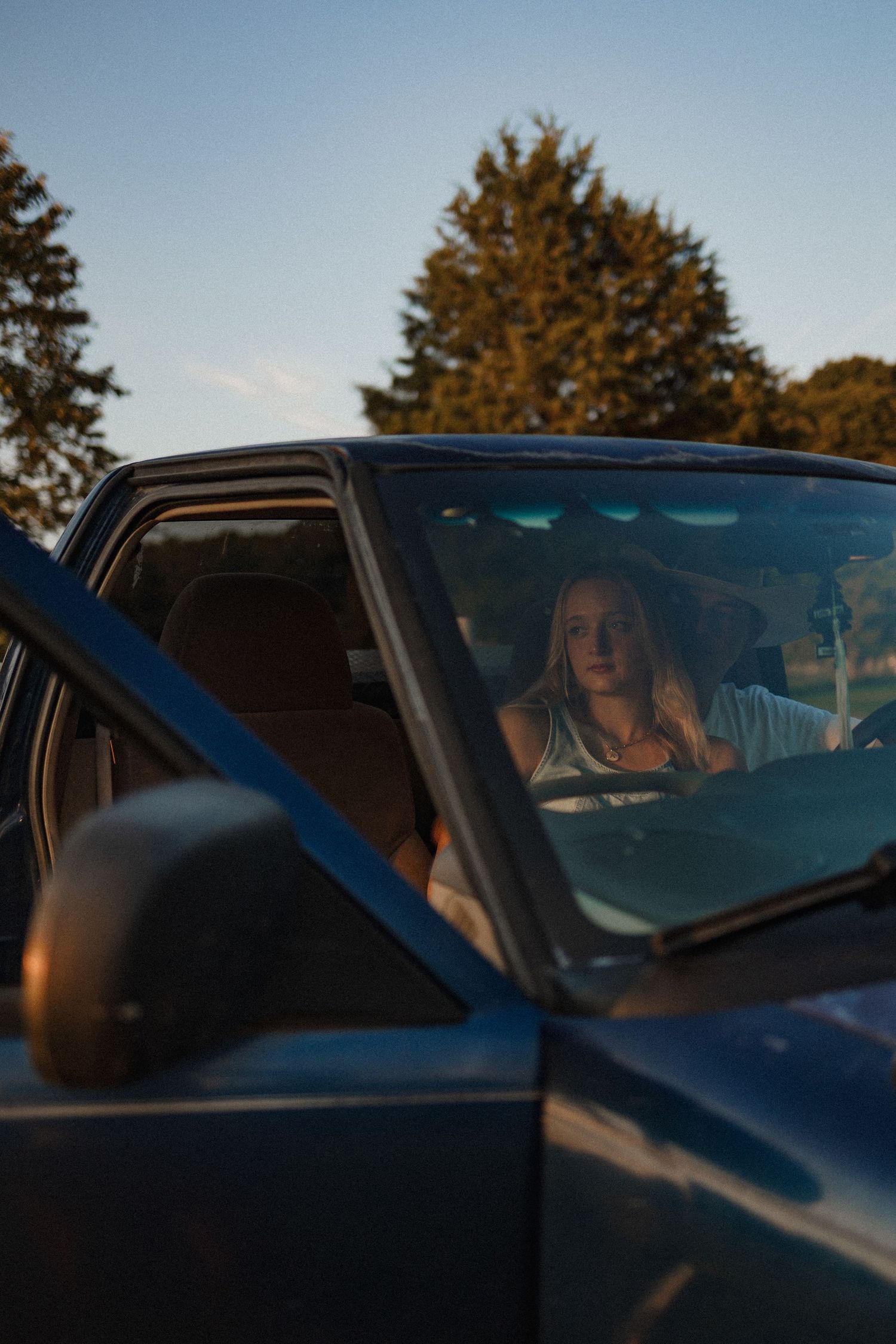 A series of four similar photos showing someone sitting in a car during sunset with golden light filtering through.