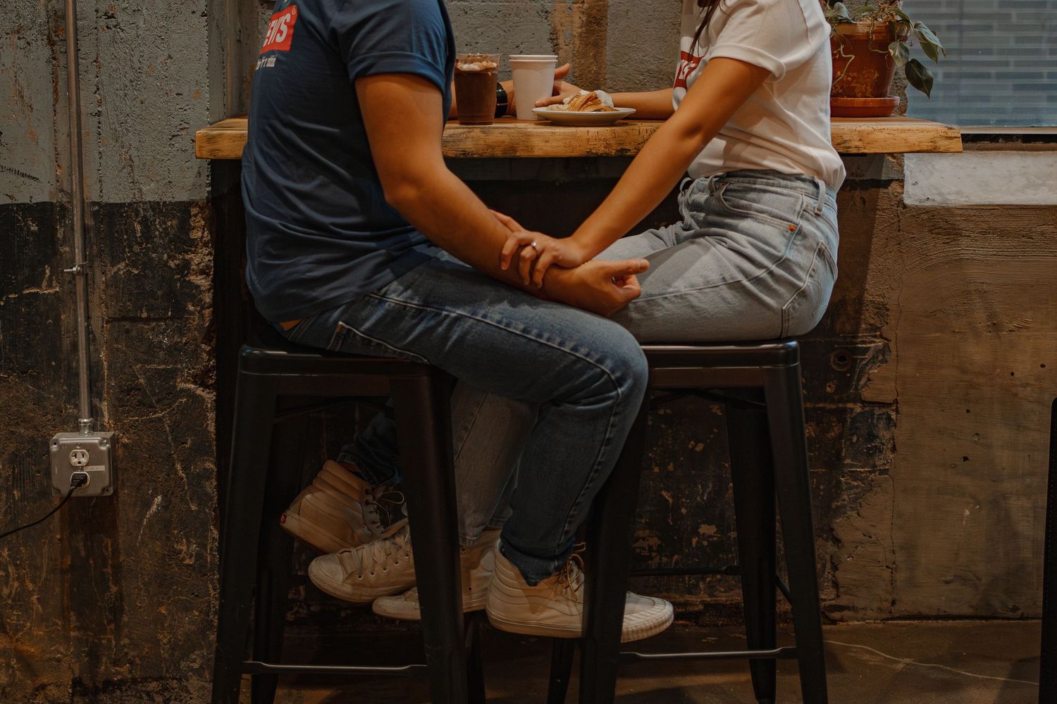 Rustic bar setting with wooden stools and brick walls in warm lighting.