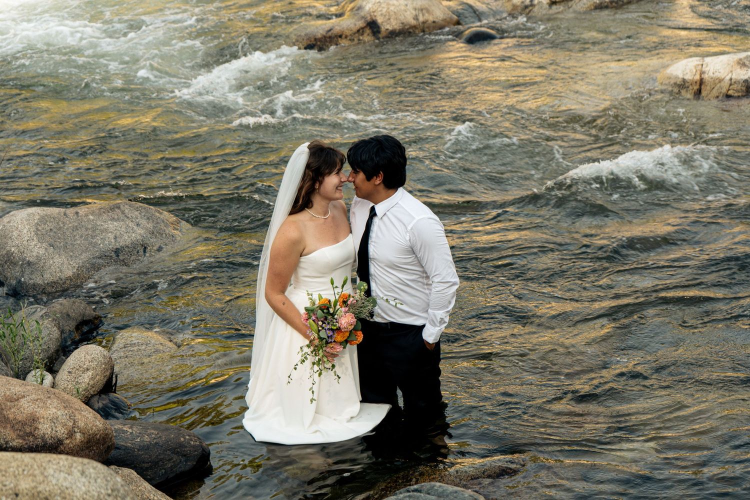 A newly married couple in a Sequoia Forest River almost kiss