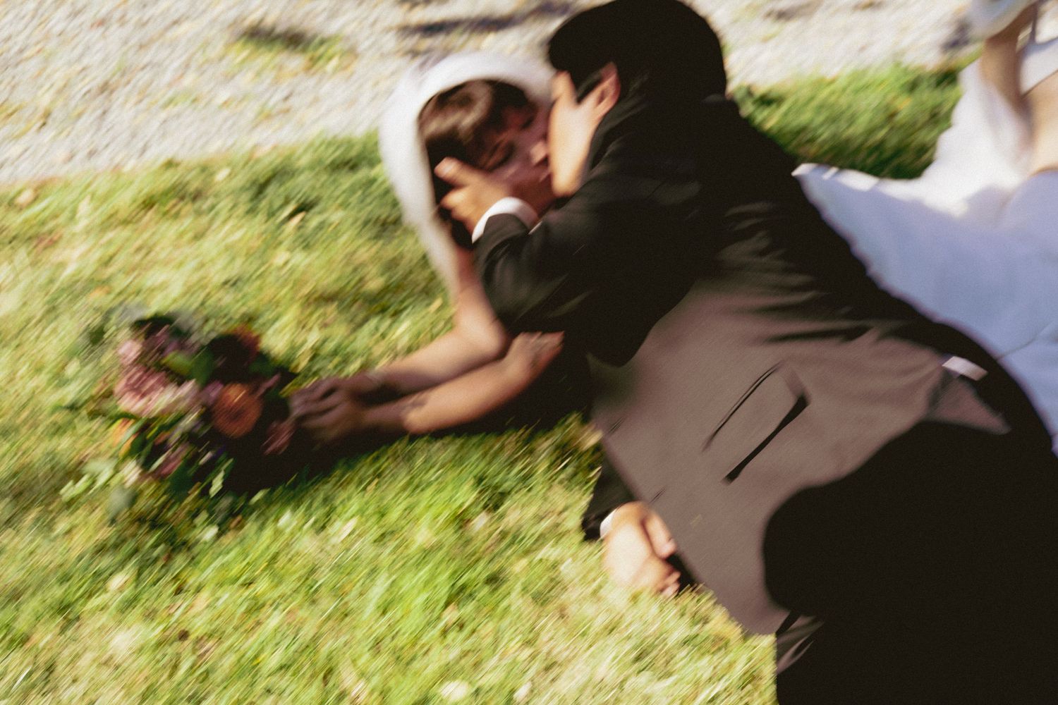 A newly married couple roll in grass