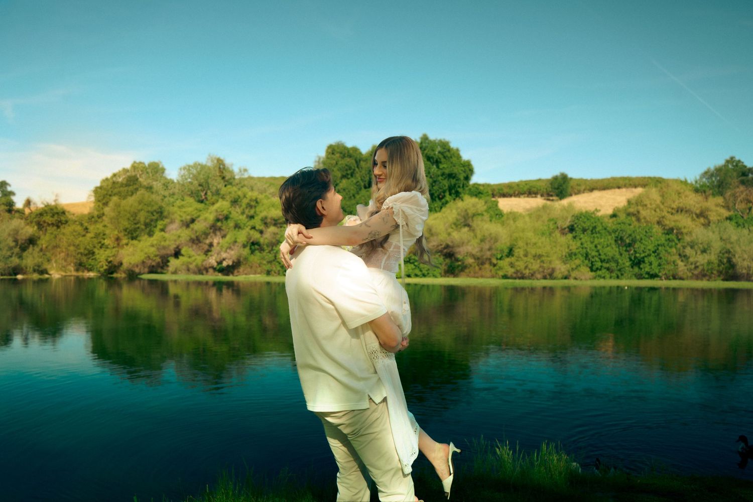 An engaged couple spin in front of Friant Lake