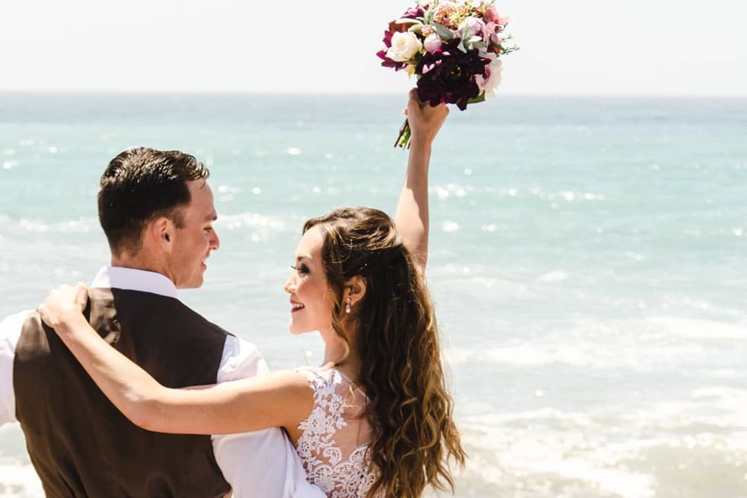 A  newly married couple in Cambria California pose in front of a beach