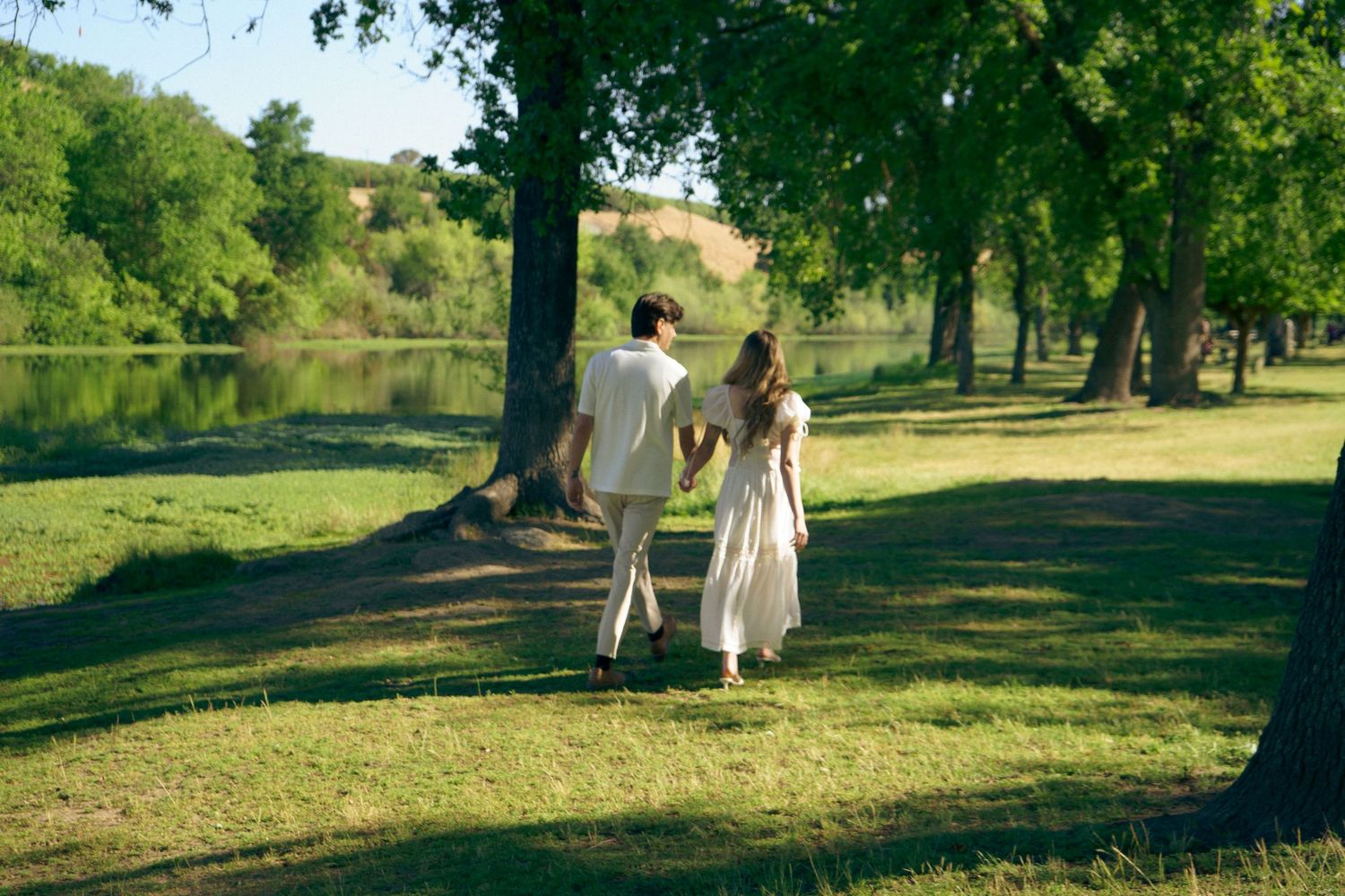 An engaged couple walk in lush green outdoors