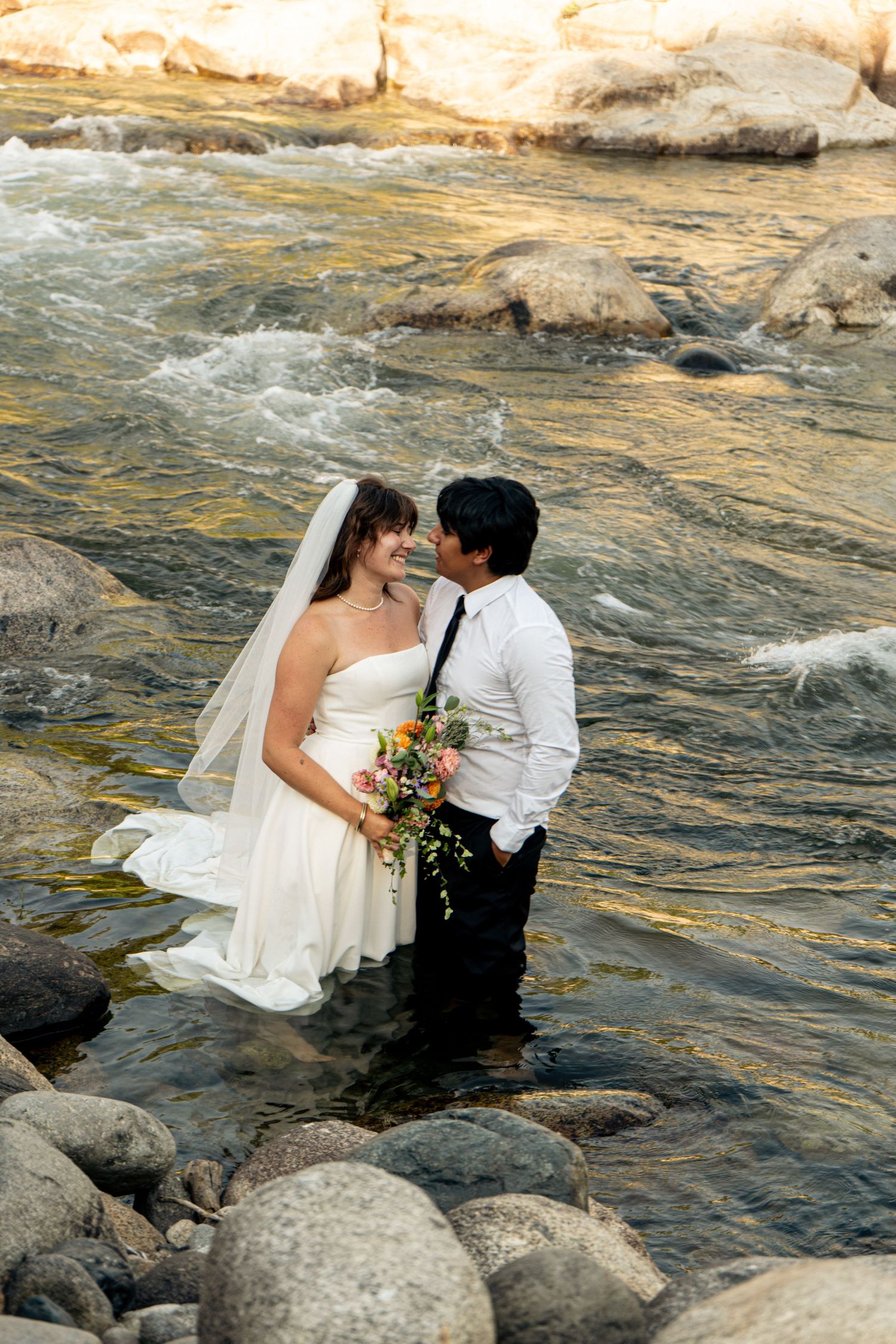 A newly married couple in a Sequoia Forest River almost kiss