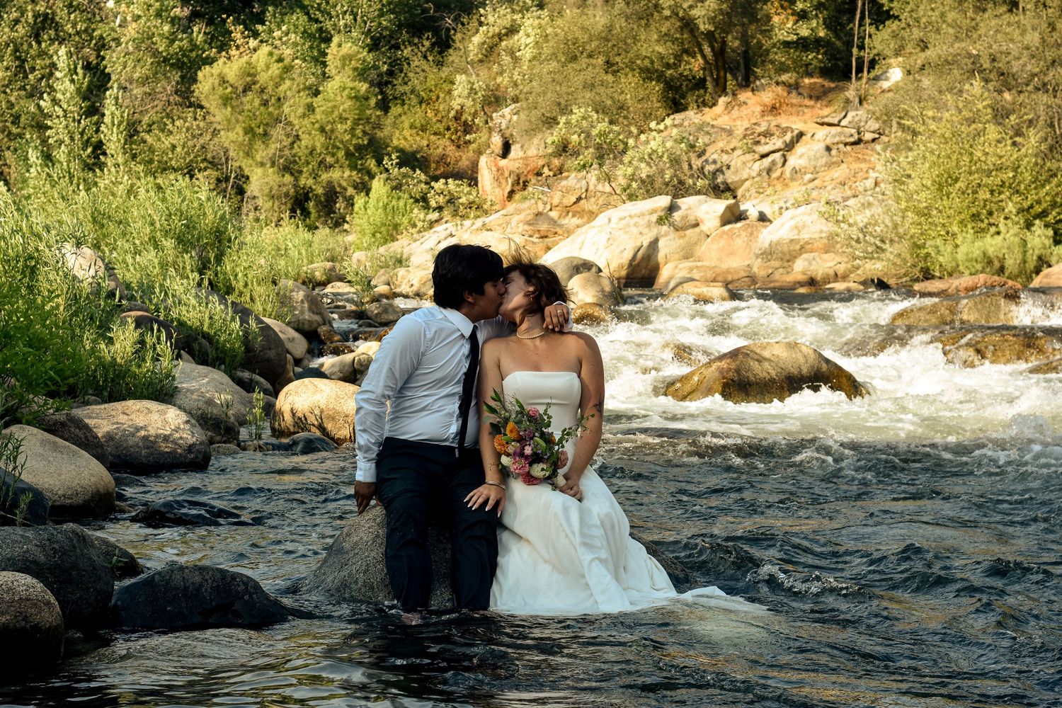 A newly married couple in a Sequoia Forest River almost kiss