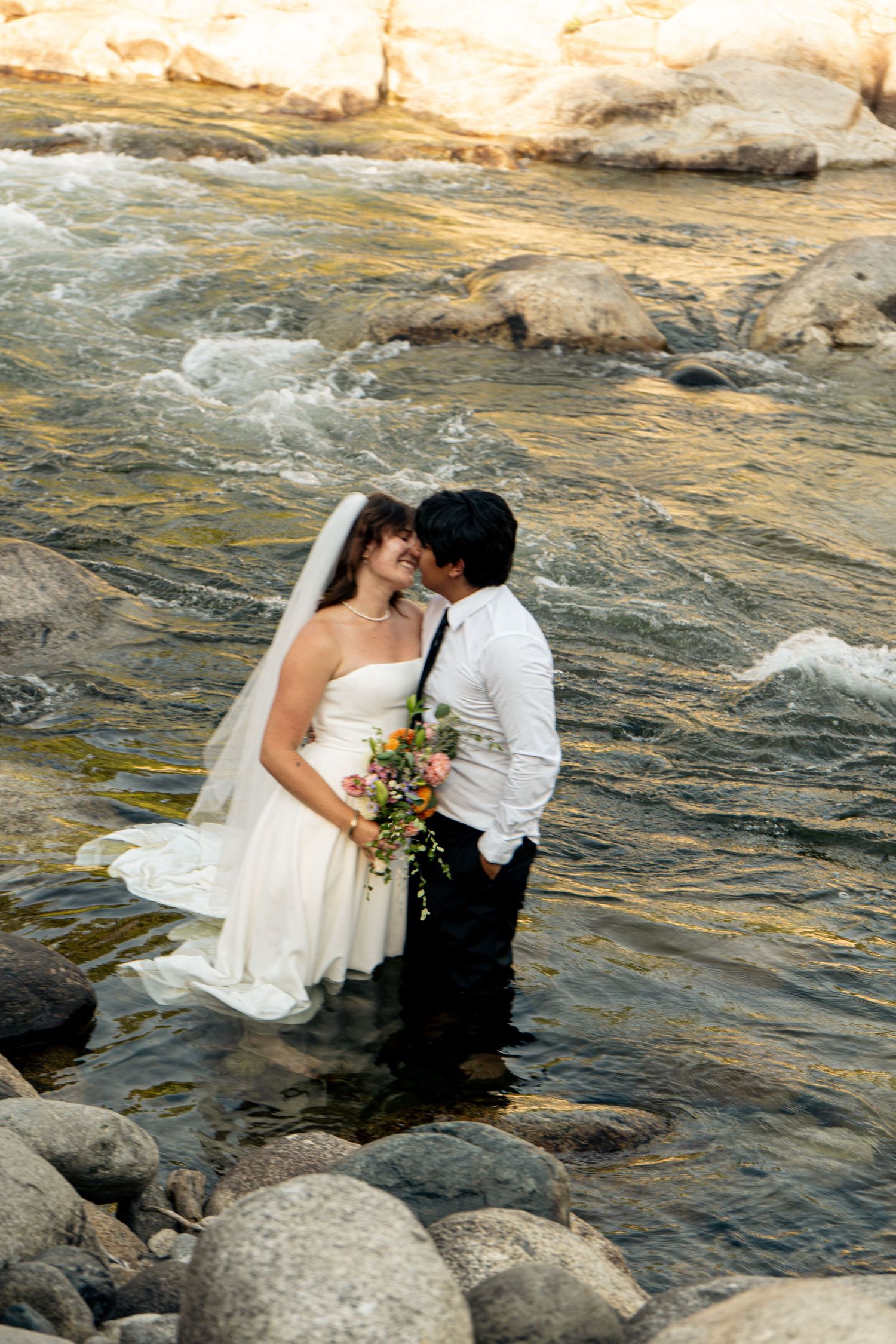 A newly married couple in a Sequoia Forest River almost kiss