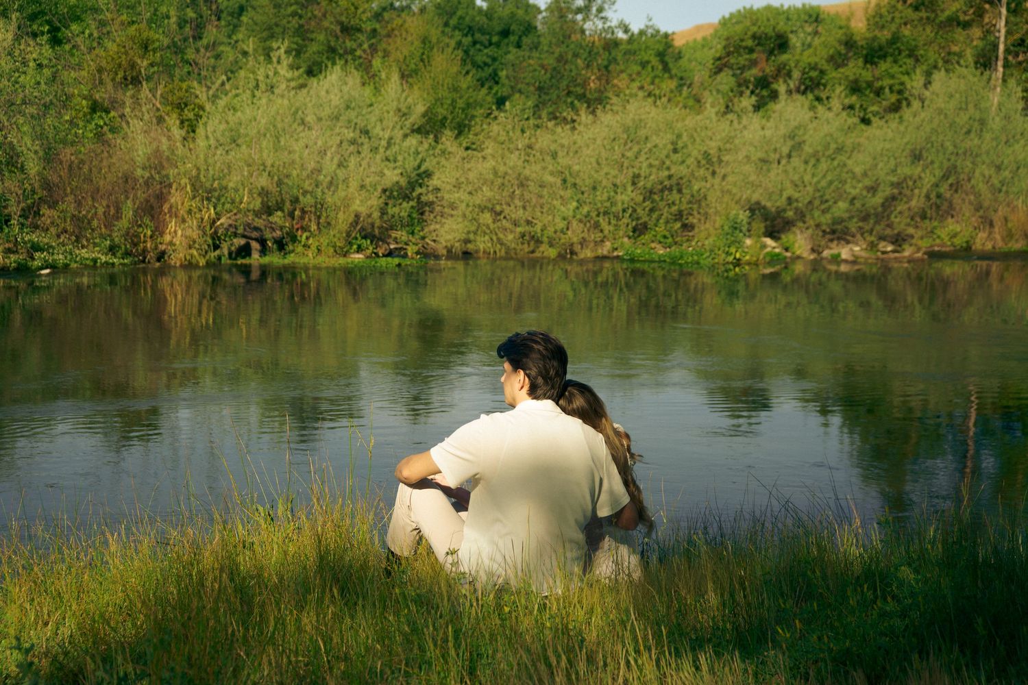 An engaged couple stare at the lake