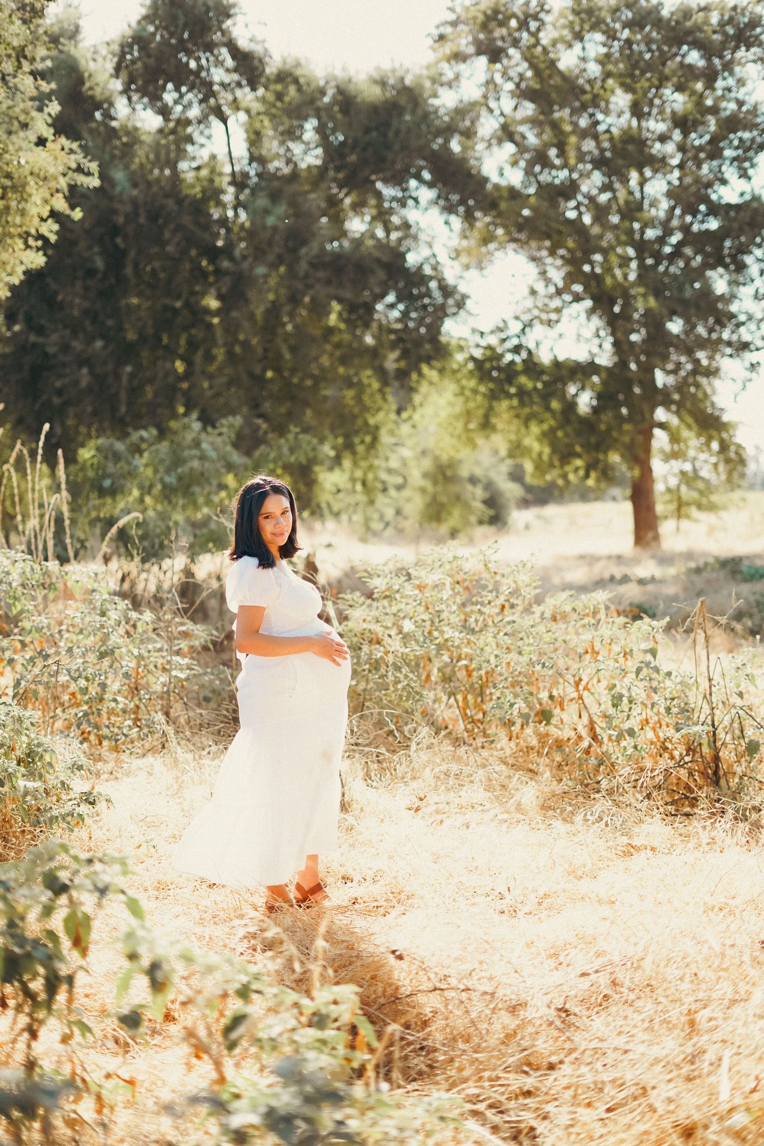 A beautiful woman poses with her pregnant tummy for maternity photos