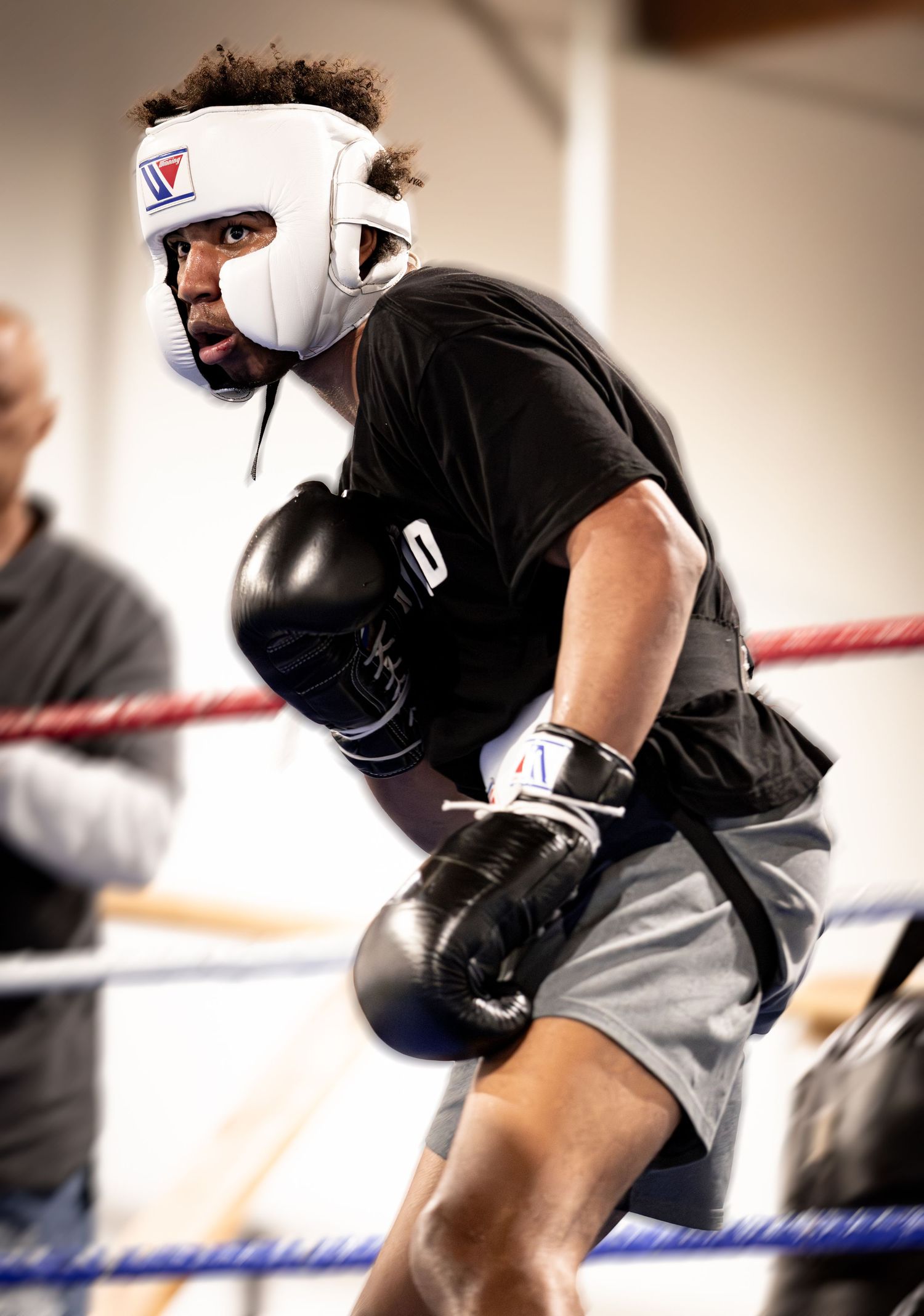 Boxer in white Victory headgear and black gloves sparring in a boxing ring during training.