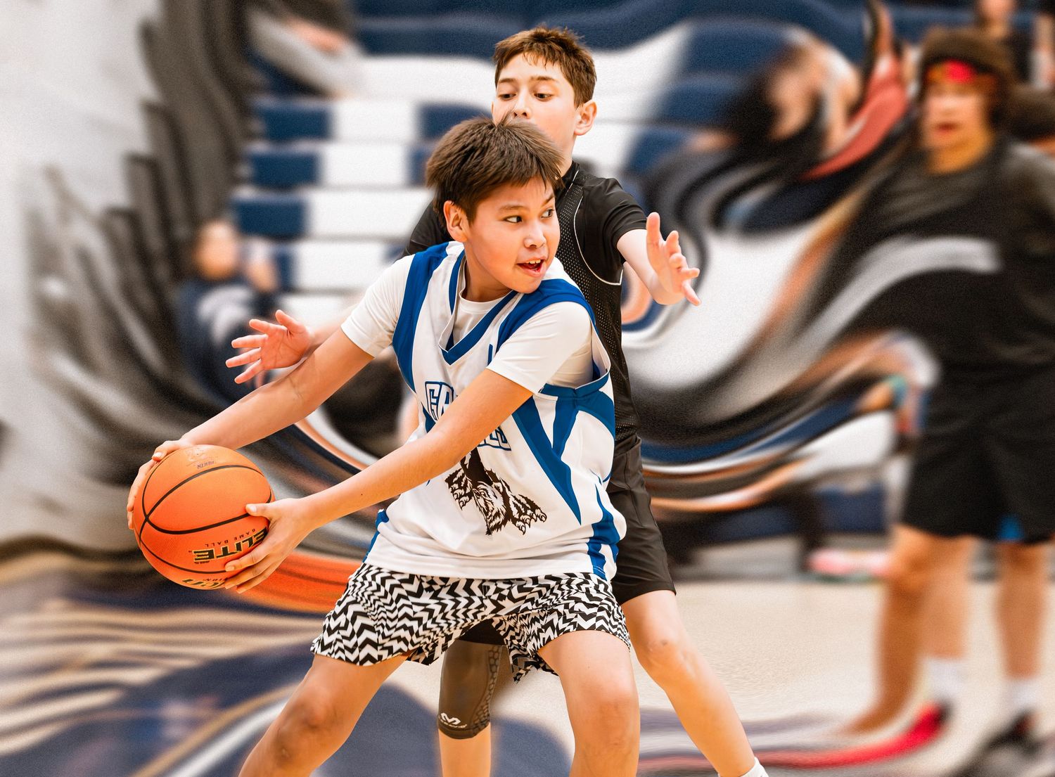 Young basketball player dribbling ball while being defended during youth league game.