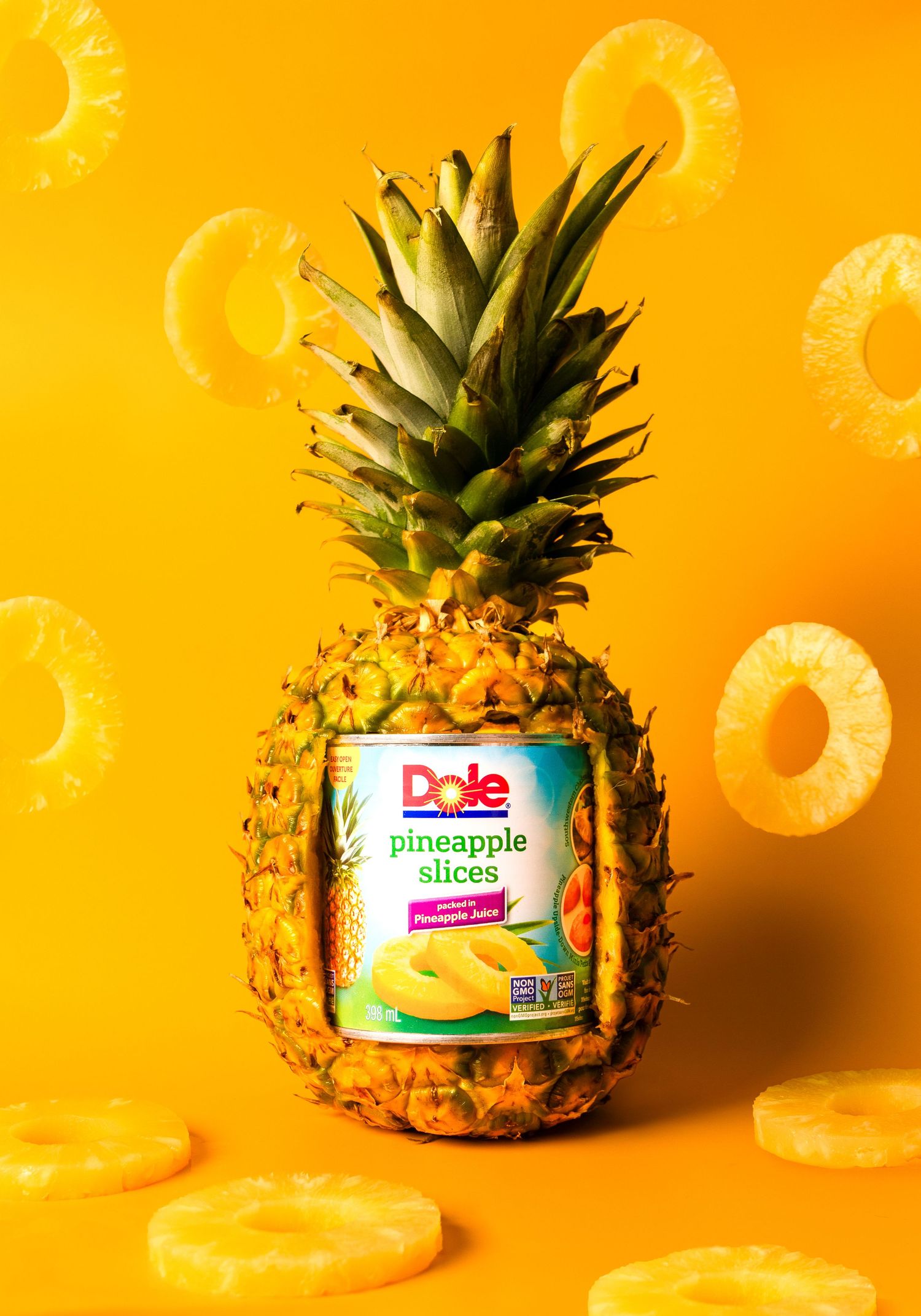 Dole pineapple slices can placed inside a whole pineapple on yellow background with pineapple rings.