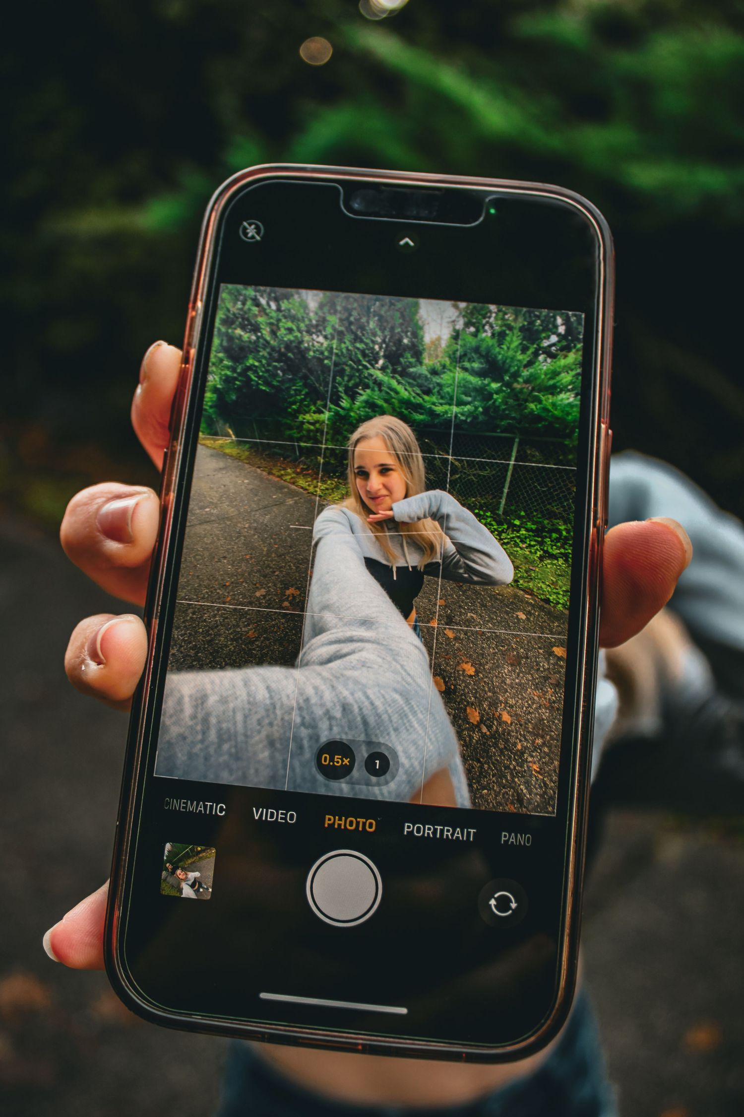 A smartphone camera being photographed with a professional camera during an outdoor portrait session.