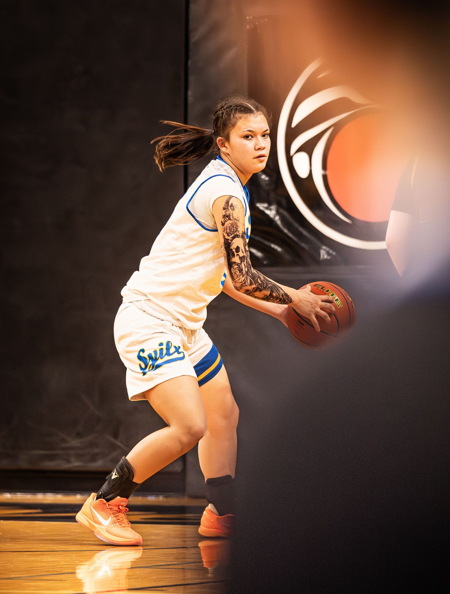 Female basketball player in Swiks uniform dribbling ball during competitive game.