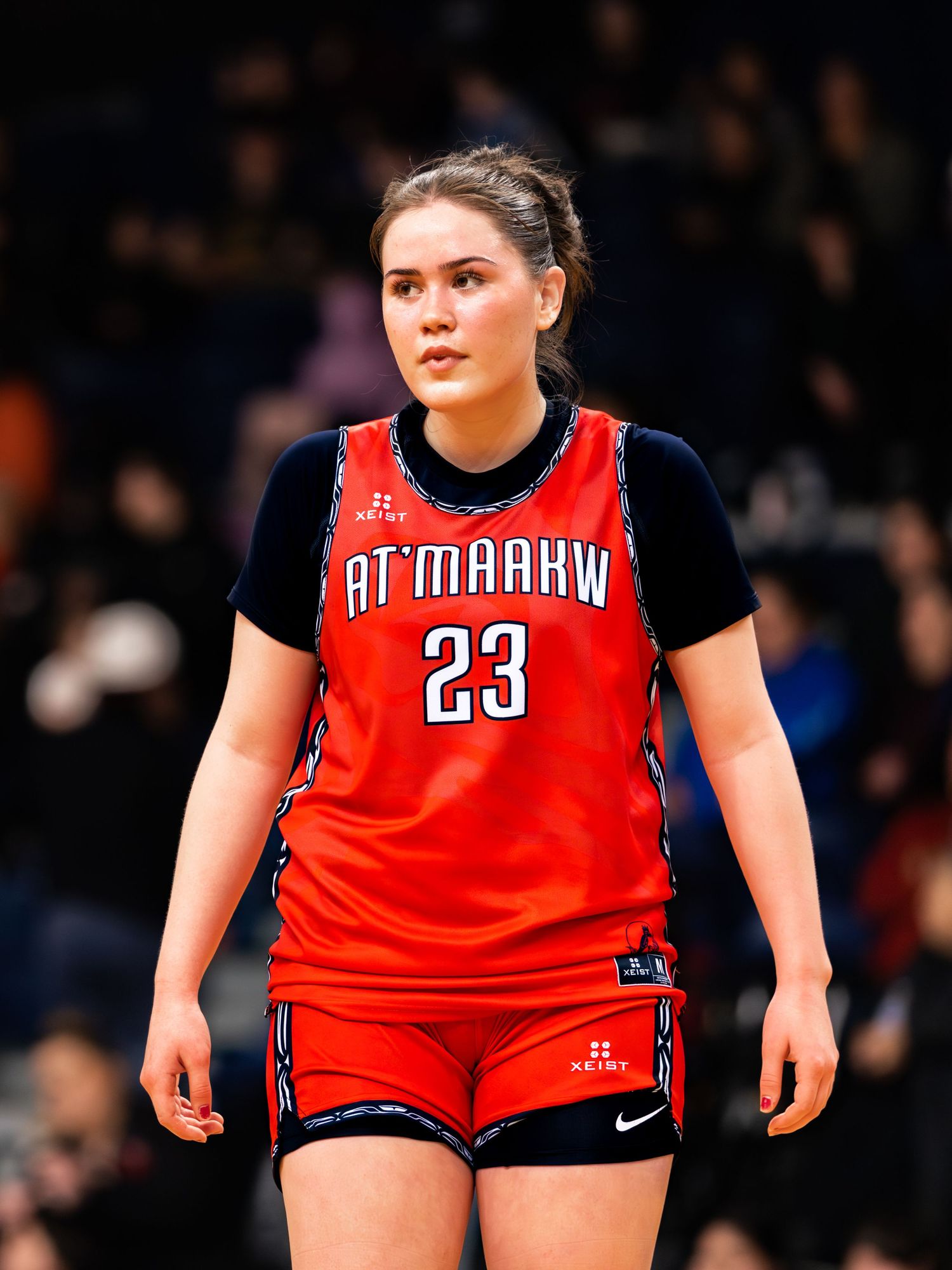 Young female basketball player in red At'maarkw number 23 jersey standing on court.