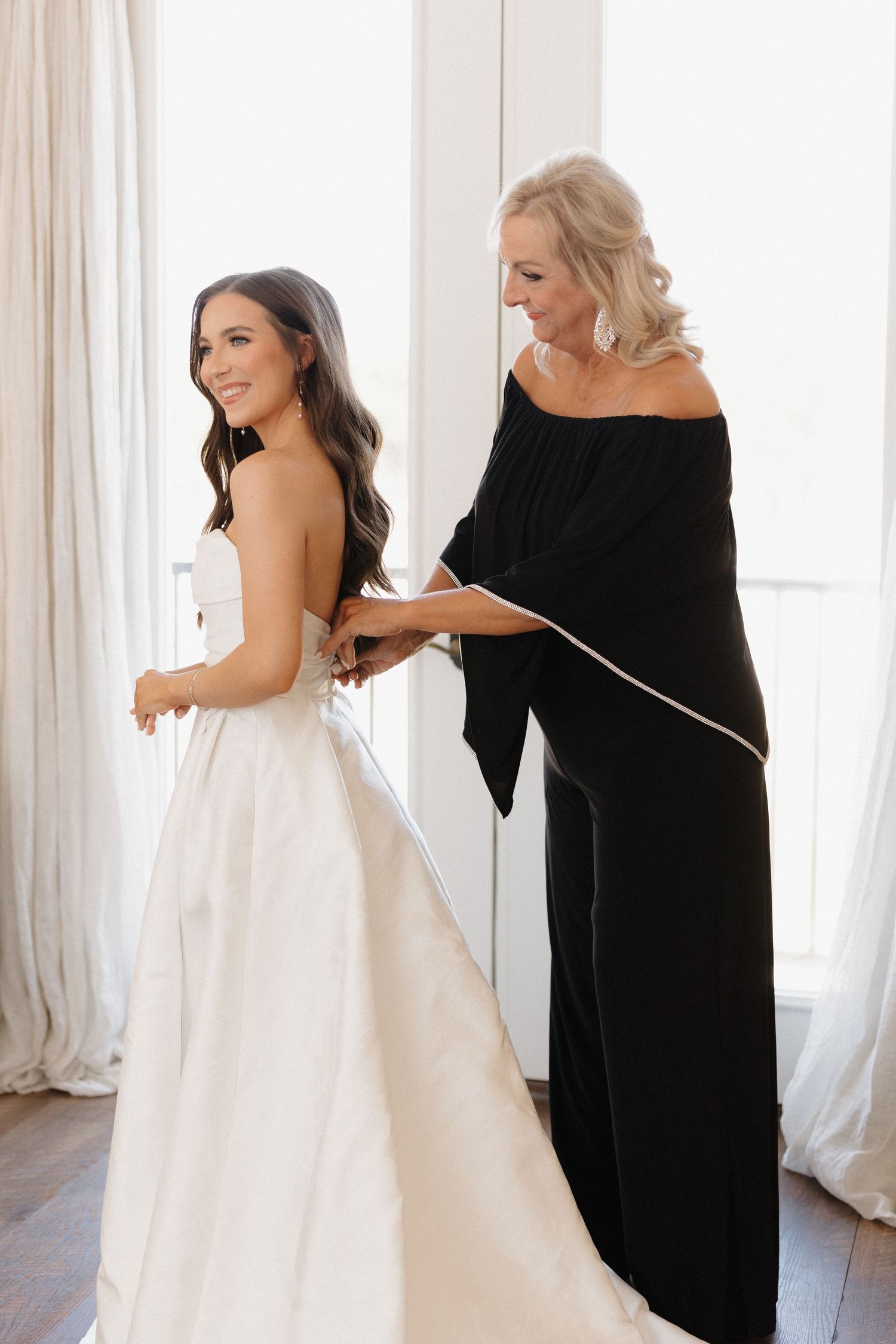 A series of photos showing a woman in black helping adjust a white wedding dress on someone in a bright sunlit room.
