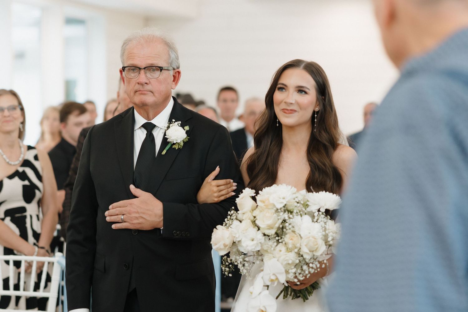 Wedding guests stand and place their hands over their hearts during an emotional ceremony moment.